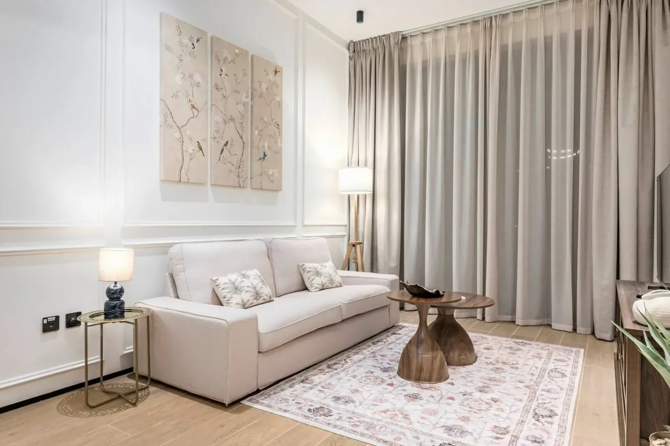 Una sala de estar luminosa con asientos, una alfombra estampada y cortinas largas.