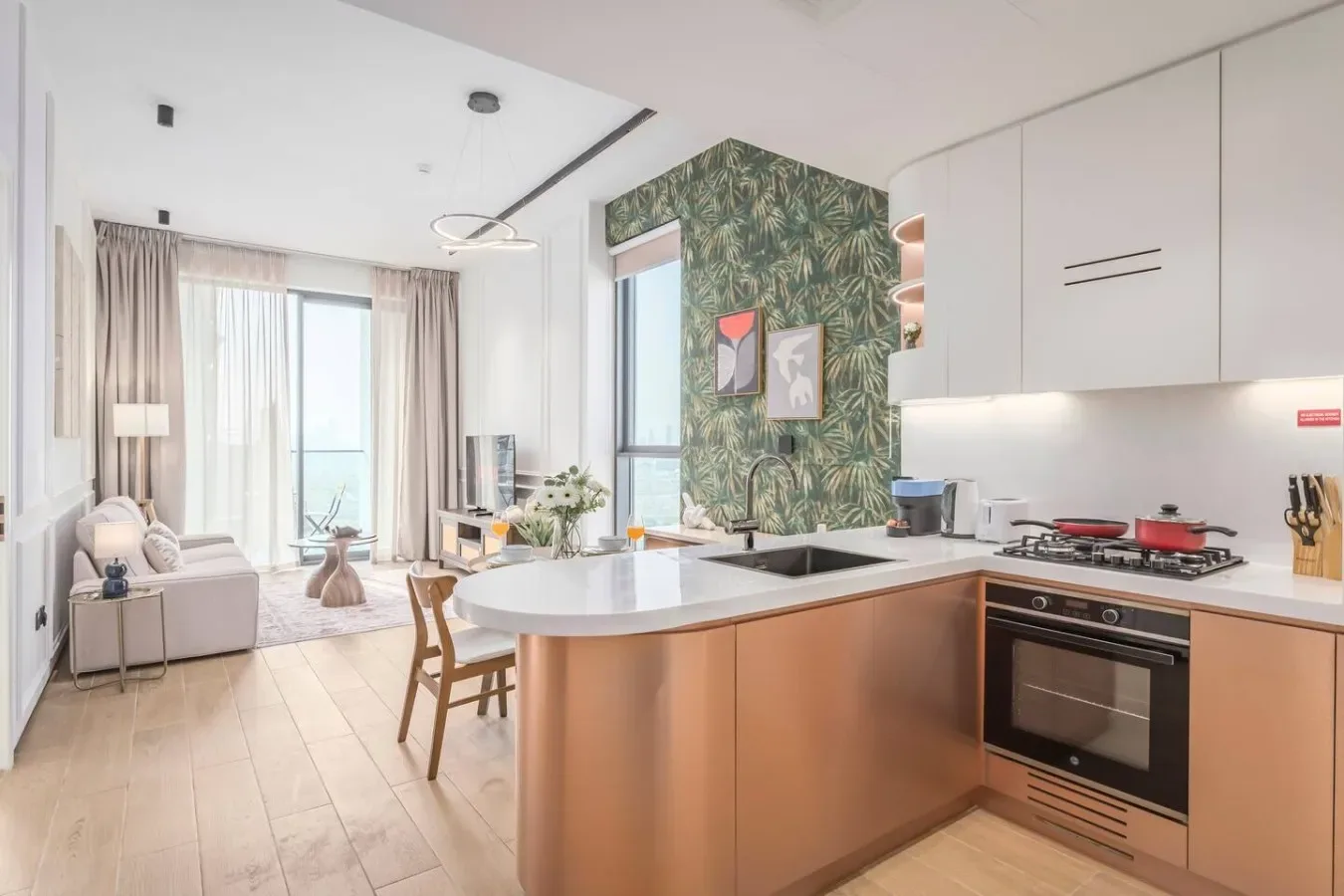 Cocina y sala de estar de planta abierta, con una isla central y asientos junto a las ventanas.
