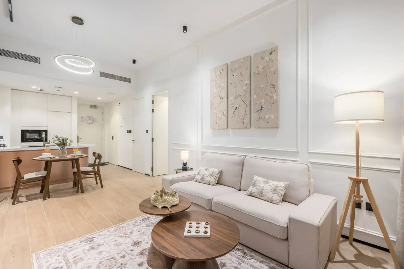 Una sala luminosa con asientos, una mesa de centro y una cocina abierta.