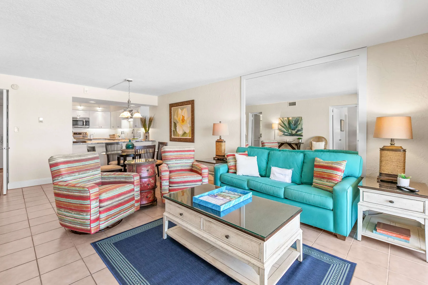 A living room with turquoise seating and a glass-topped coffee table.