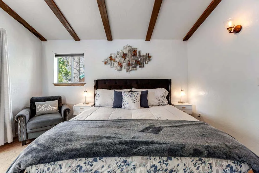 Dormitorio con una cama grande, mesillas de noche y vigas expuestas en el techo.