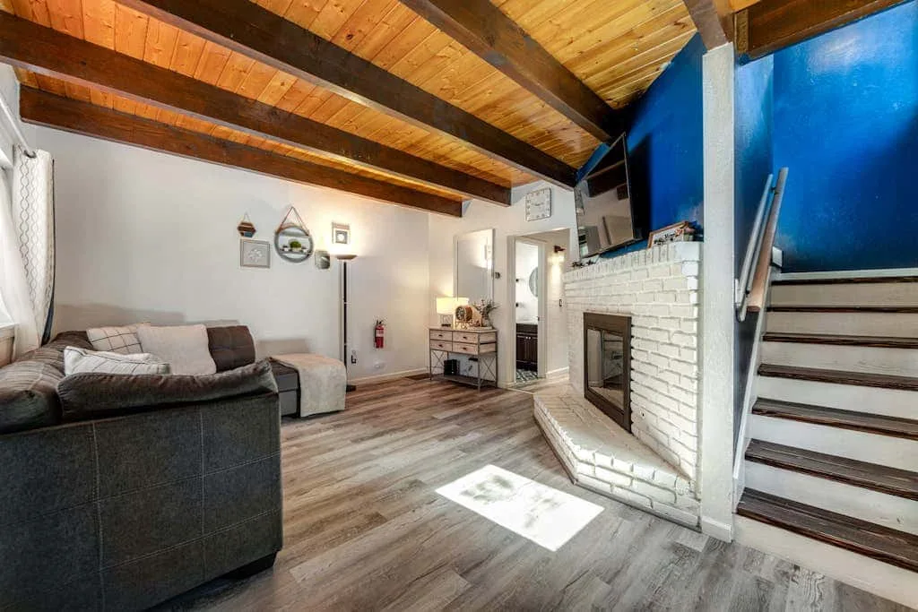 Una sala de estar con asientos, una chimenea de ladrillo y un techo alto de madera.