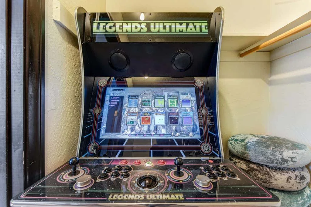 Una máquina recreativa está junto a un asiento acolchado en un pequeño espacio interior.