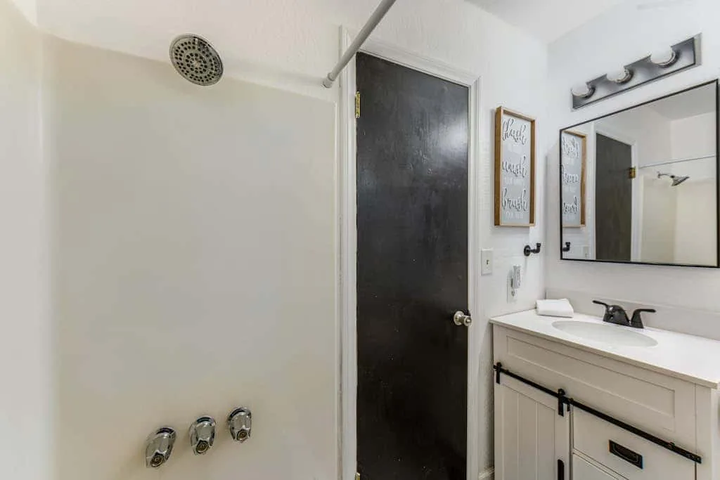 Un baño con ducha, mueble de lavabo y espejo.