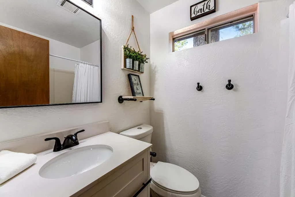 Un baño con lavabo, espejo e inodoro.