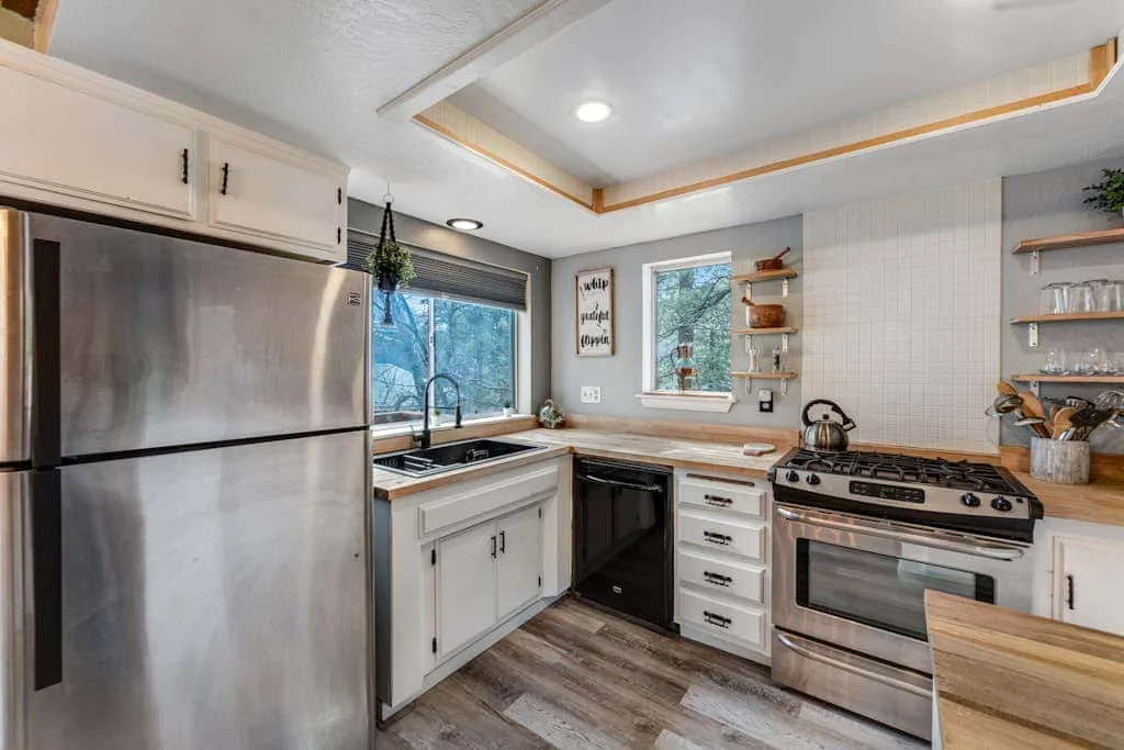 Una cocina luminosa con gabinetes blancos, un refrigerador grande y una estufa.