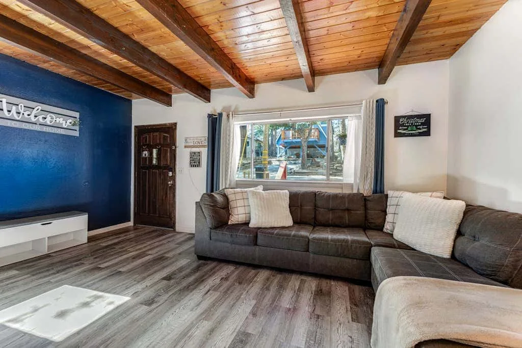 A living room with a sectional sofa beneath a wood-paneled ceiling.