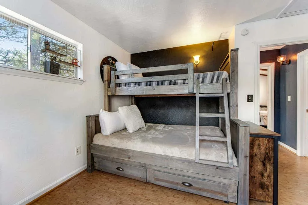 Un dormitorio con una litera de madera y una ventana en la pared.