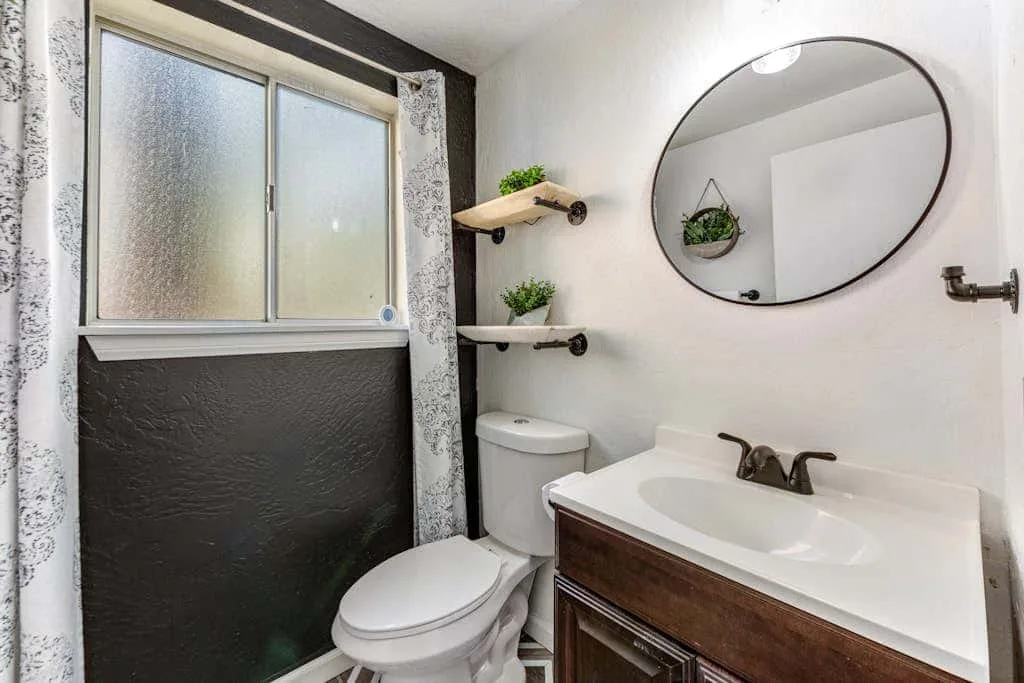 Un baño con lavabo, inodoro y ventana esmerilada.