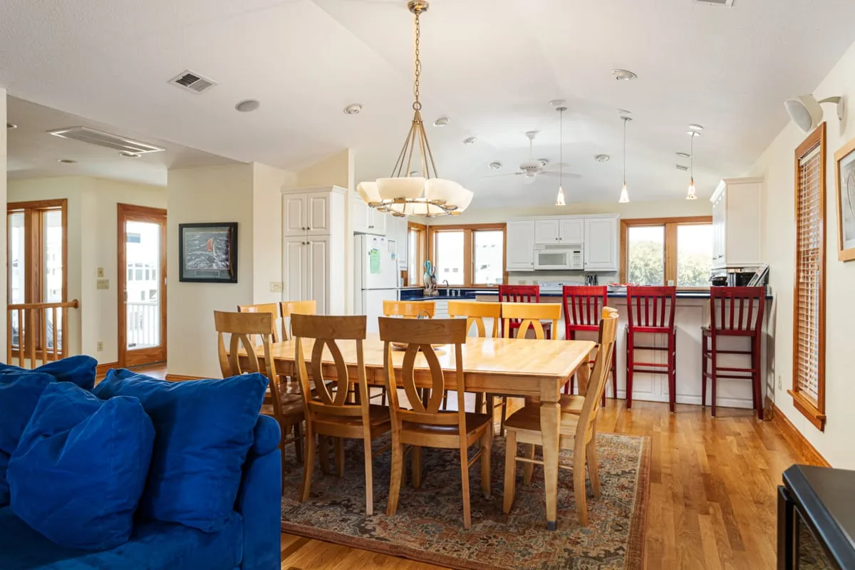 Un espacio abierto de comedor y cocina cuenta con una mesa de madera y taburetes rojos.