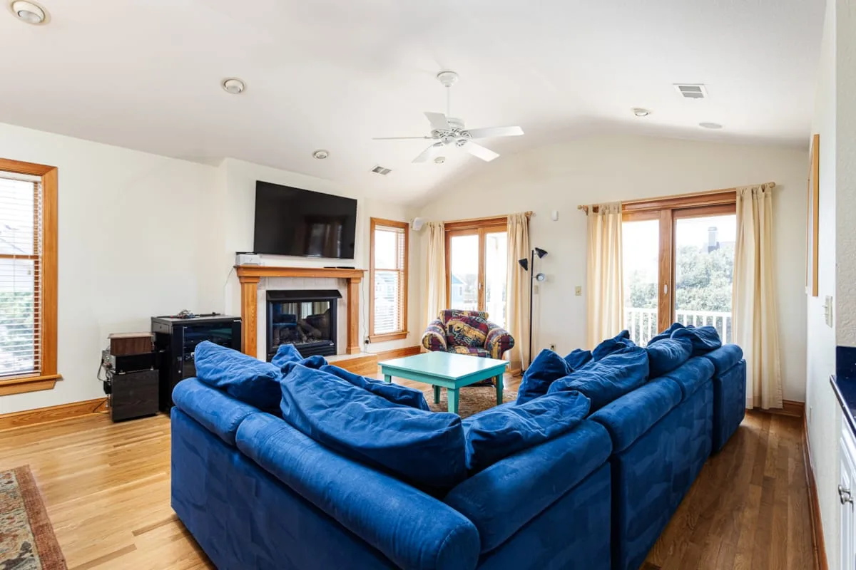 Una sala de estar con asientos azules alrededor de una mesa de centro y una chimenea.