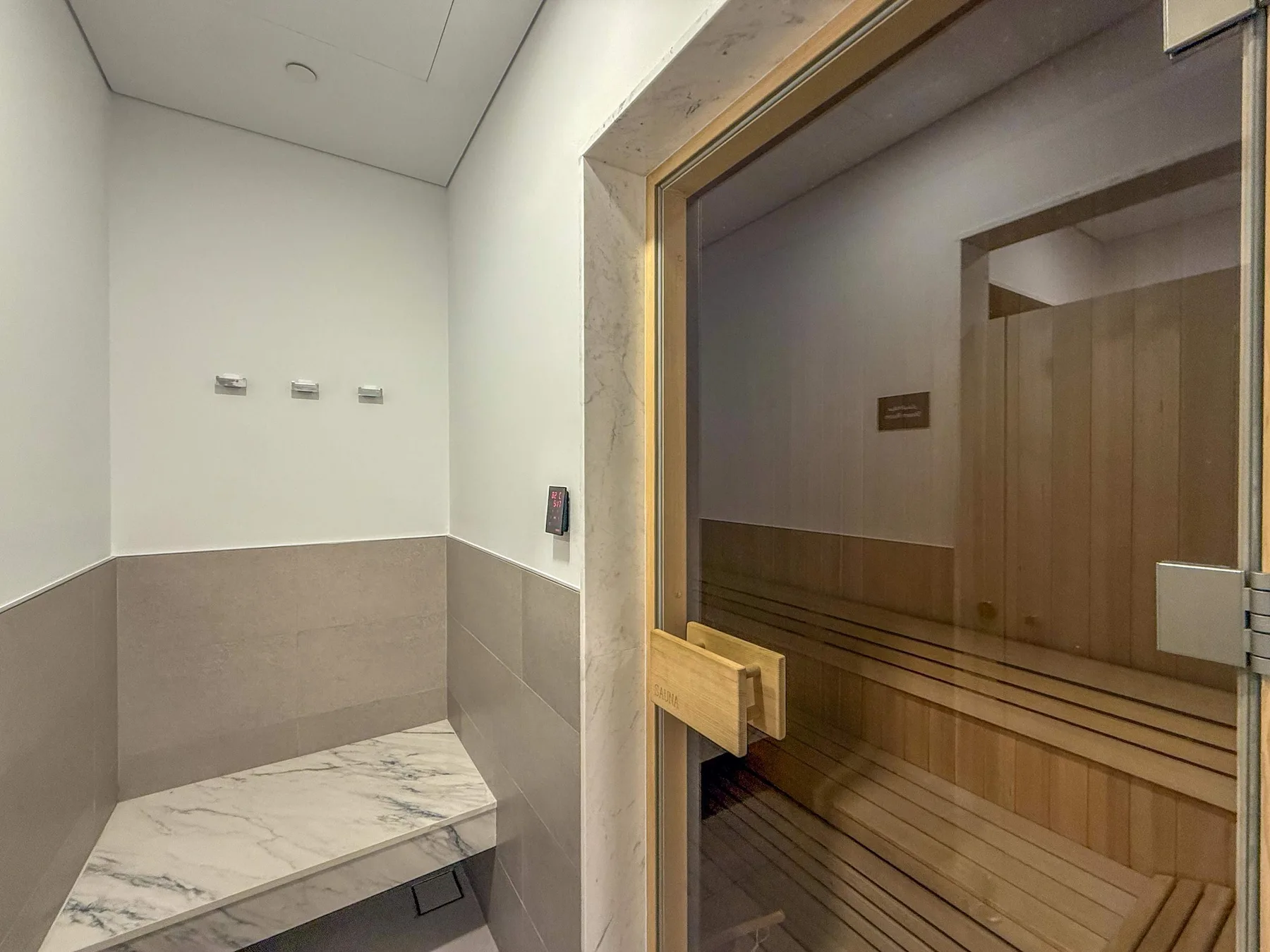 Una sauna con un banco de madera y un banco de mármol en primer plano.