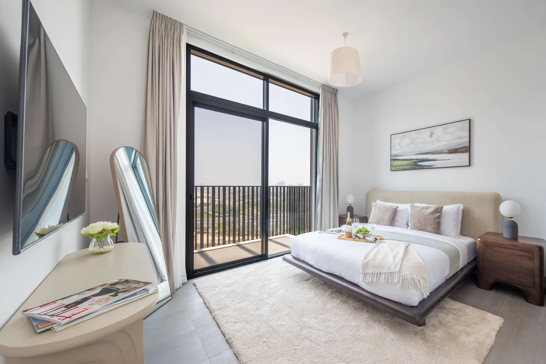 Un dormitorio luminoso con una cama, mesitas de noche y grandes puertas de cristal hacia un balcón.