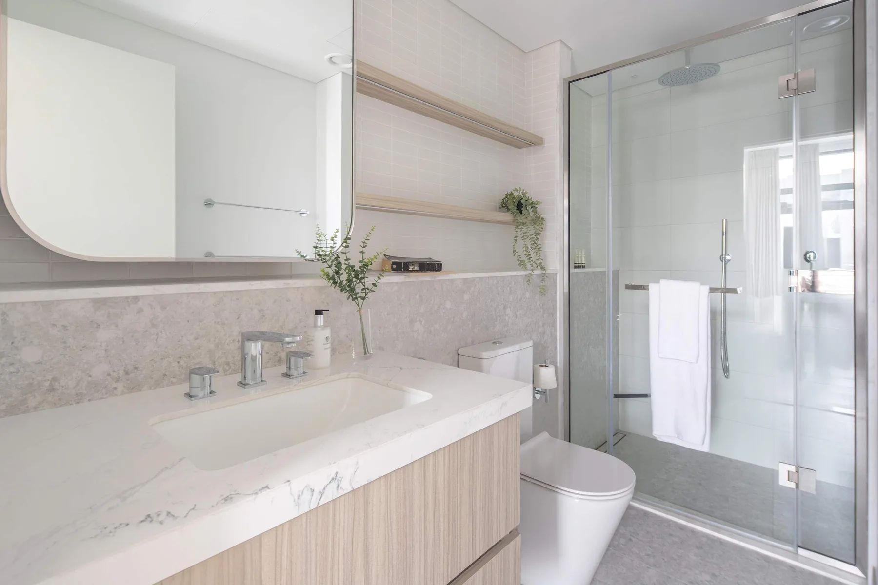 Un baño luminoso con un amplio lavabo y una ducha con mampara de vidrio.