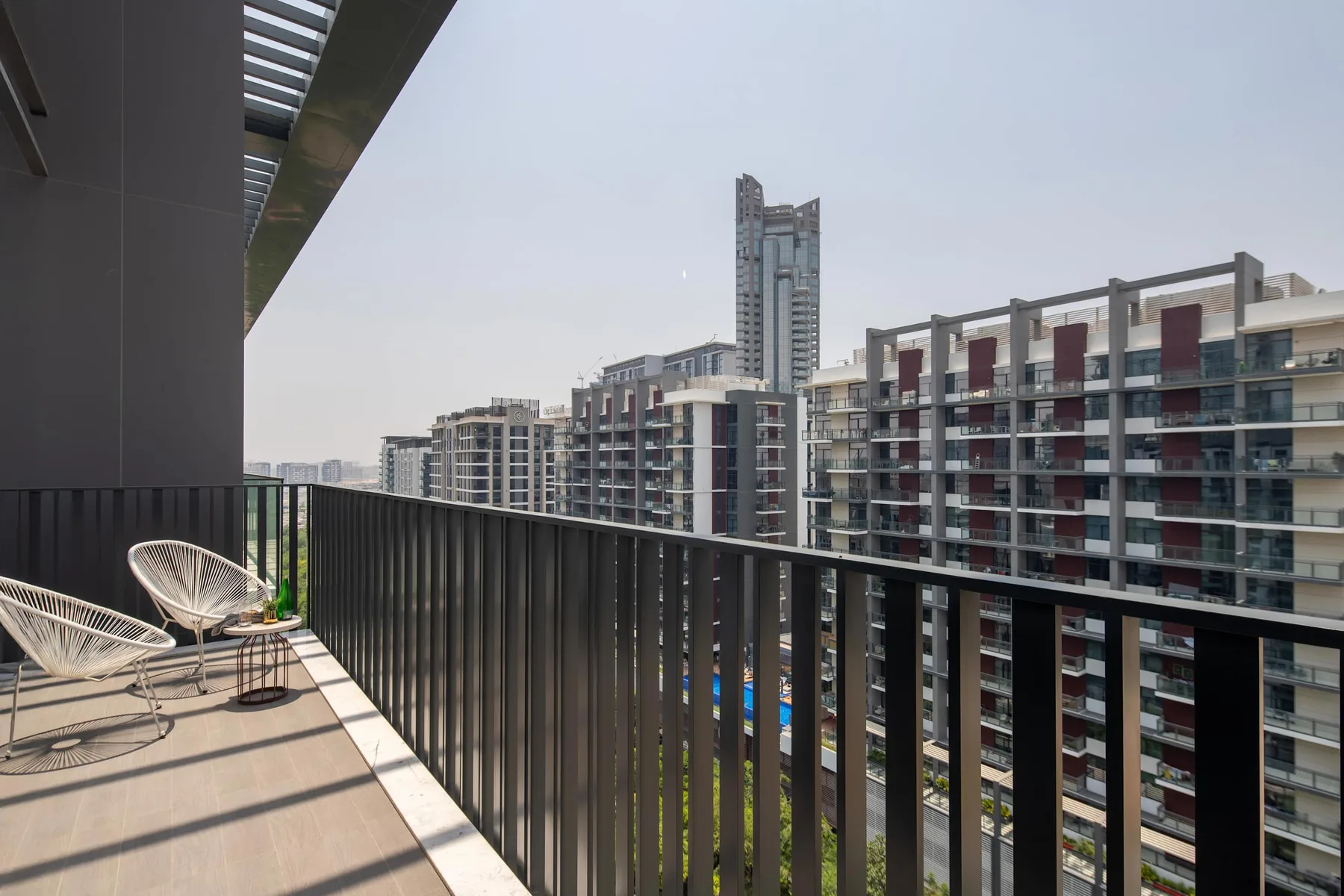 Un balcón da a edificios de apartamentos cercanos, con asientos junto a la barandilla.