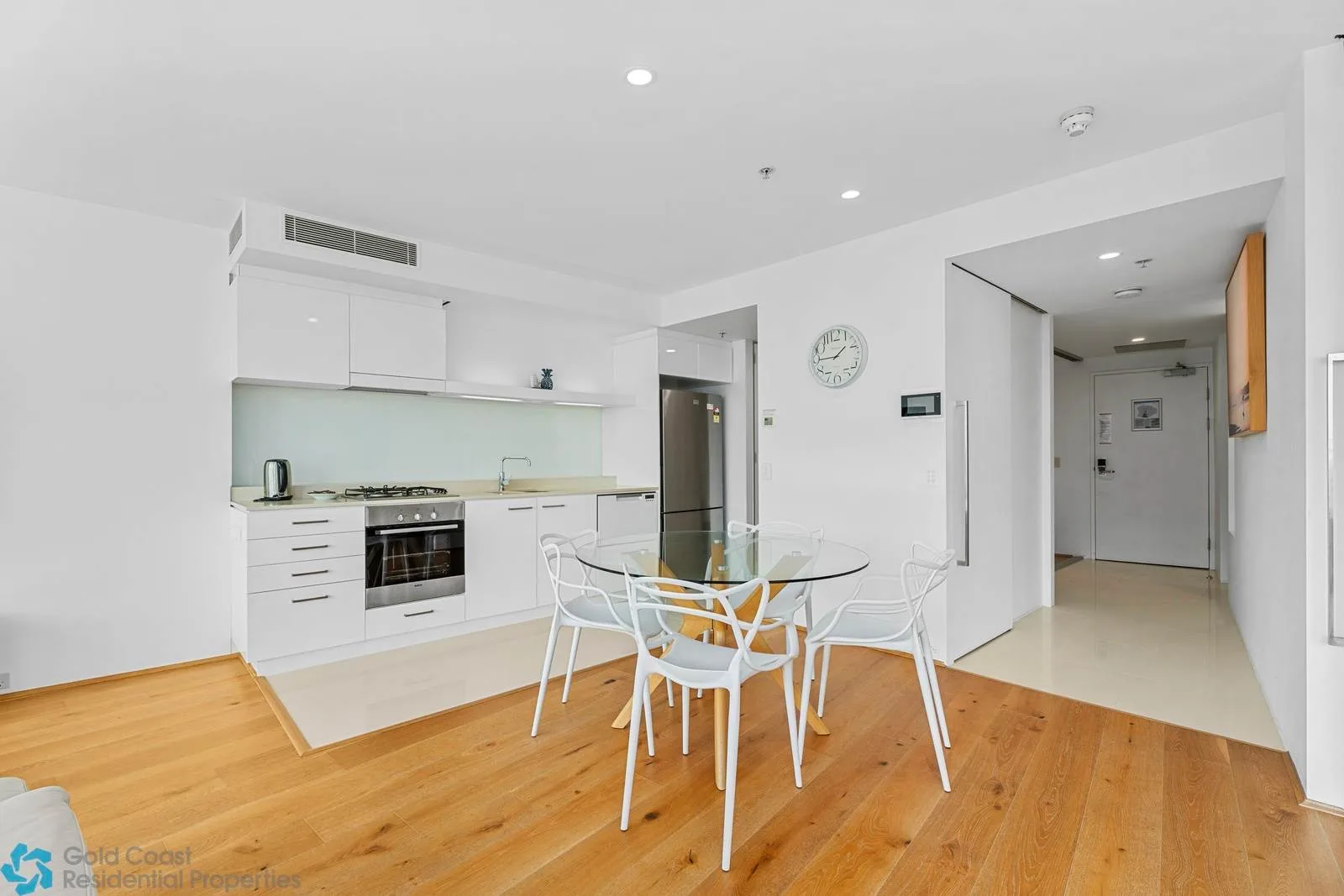Una luminosa cocina abierta con comedor y una mesa de vidrio.