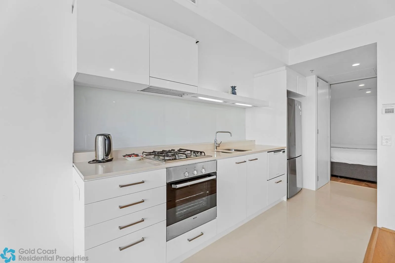 Una cocina moderna y luminosa con armarios blancos, una placa de cocina y un horno.