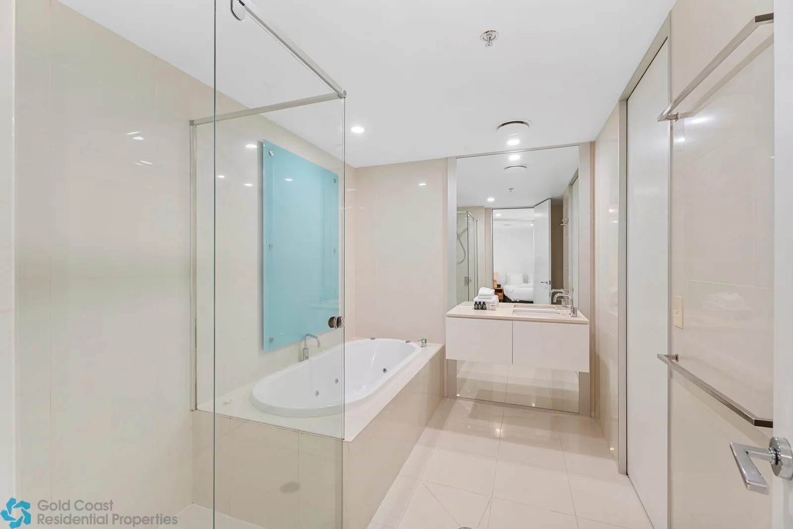 Un baño luminoso con bañera, mampara de vidrio y un lavabo amplio.