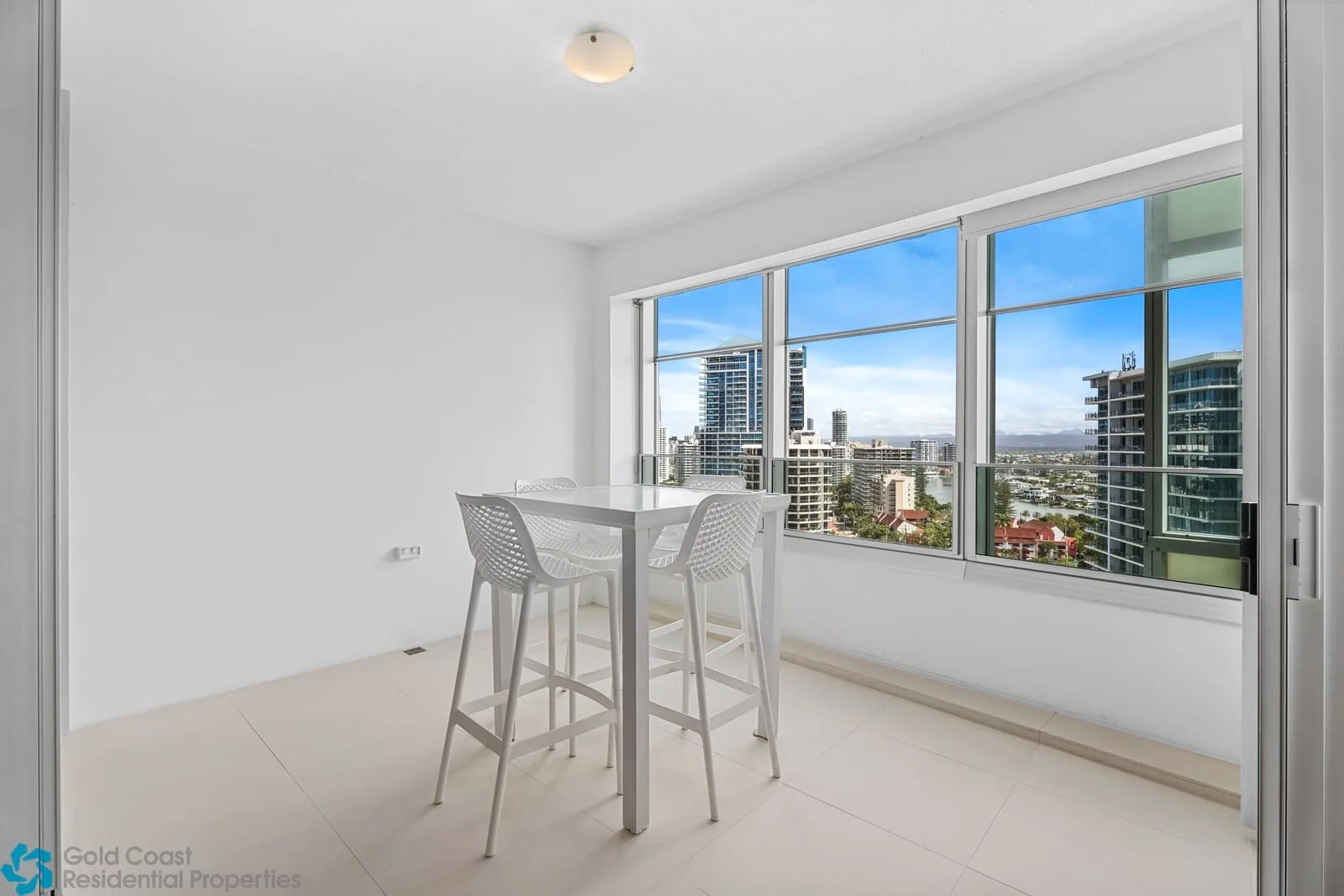 Un comedor luminoso con mesa y asientos junto a grandes ventanas.