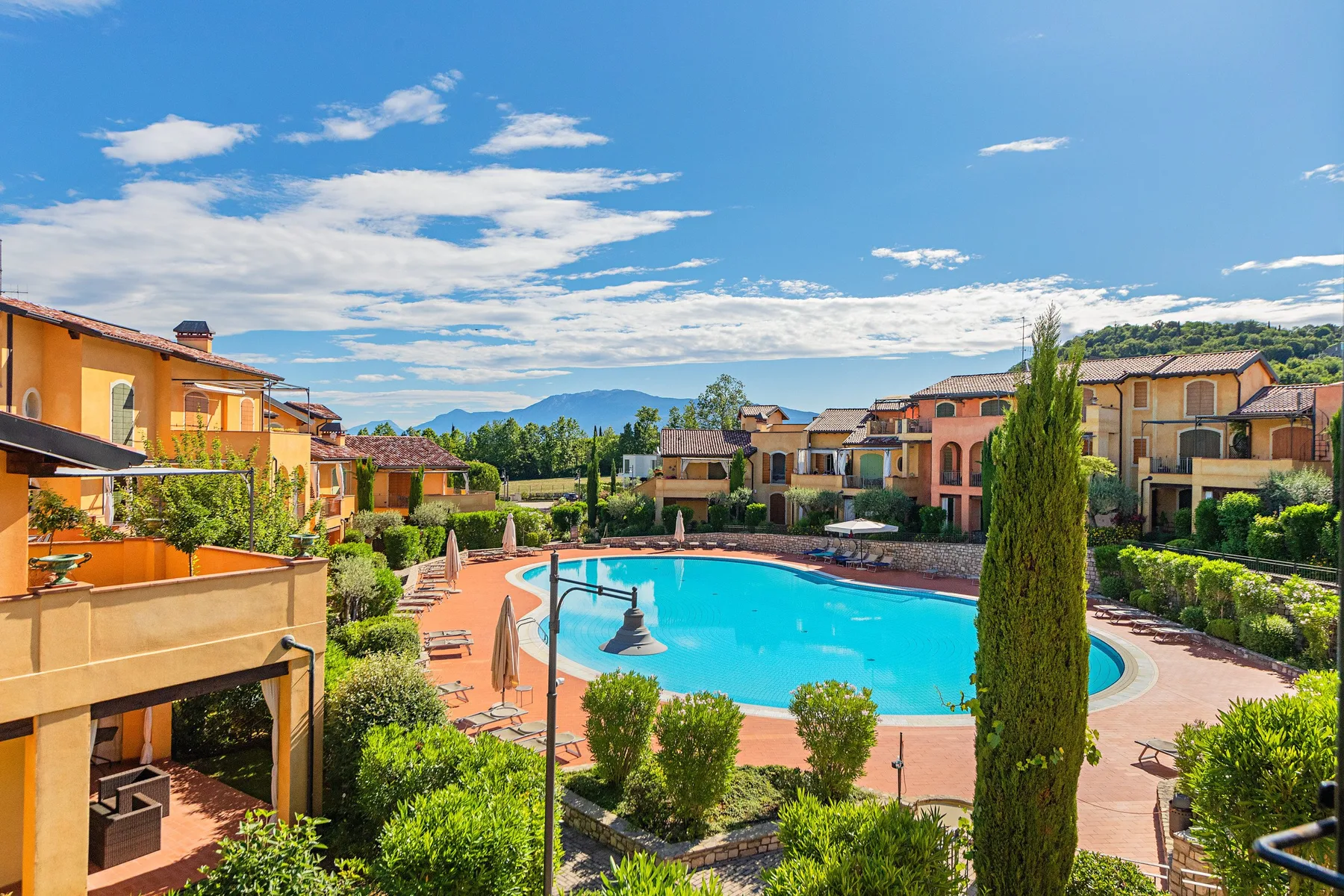 A swimming pool sits among landscaped grounds and colorful residential buildings.