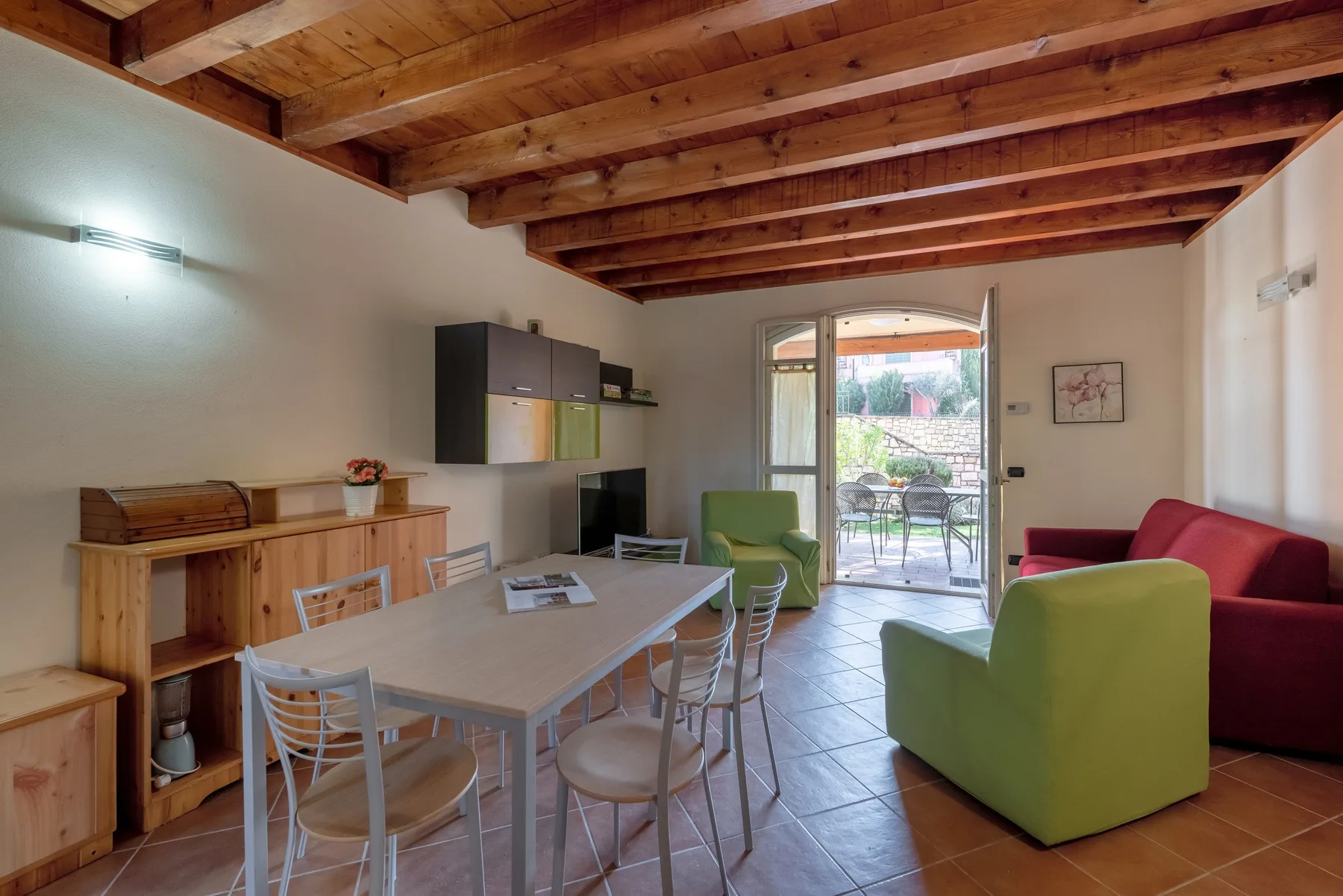 A dining and living area with a table, seating, and an open patio doorway.
