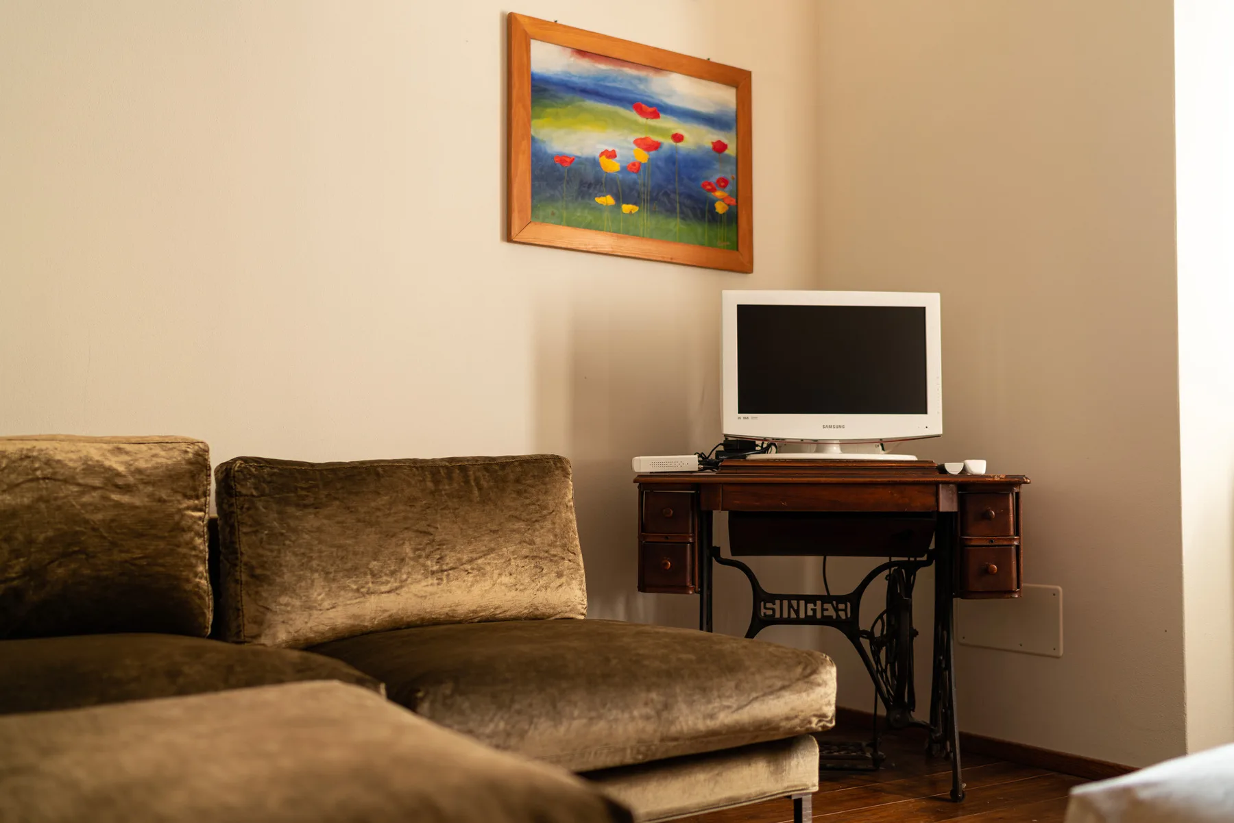 Una sala de estar con un sofá marrón, un televisor y arte colorido en la pared.