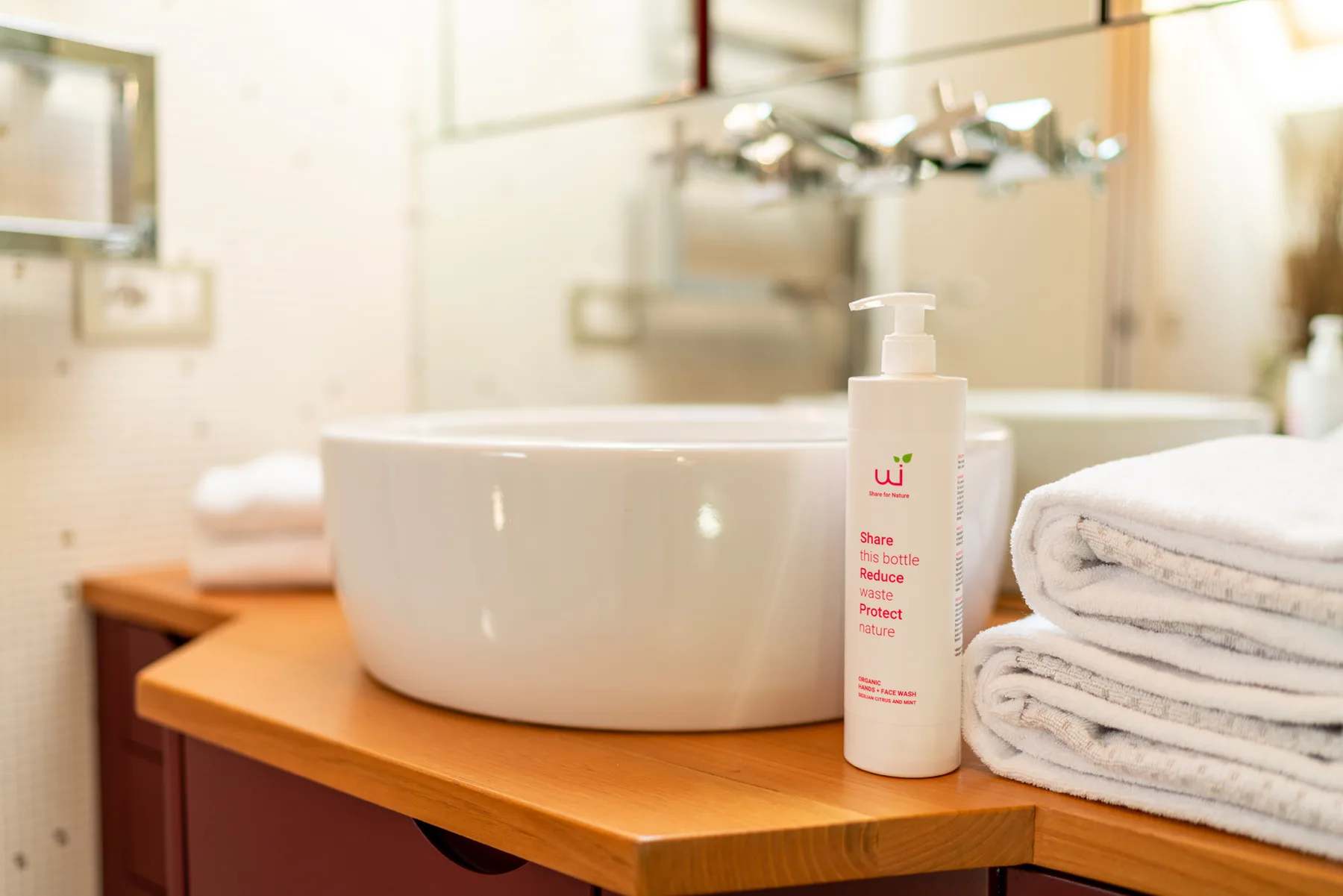 Un tocador de baño tiene un lavabo blanco sobre encimera y toallas dobladas.