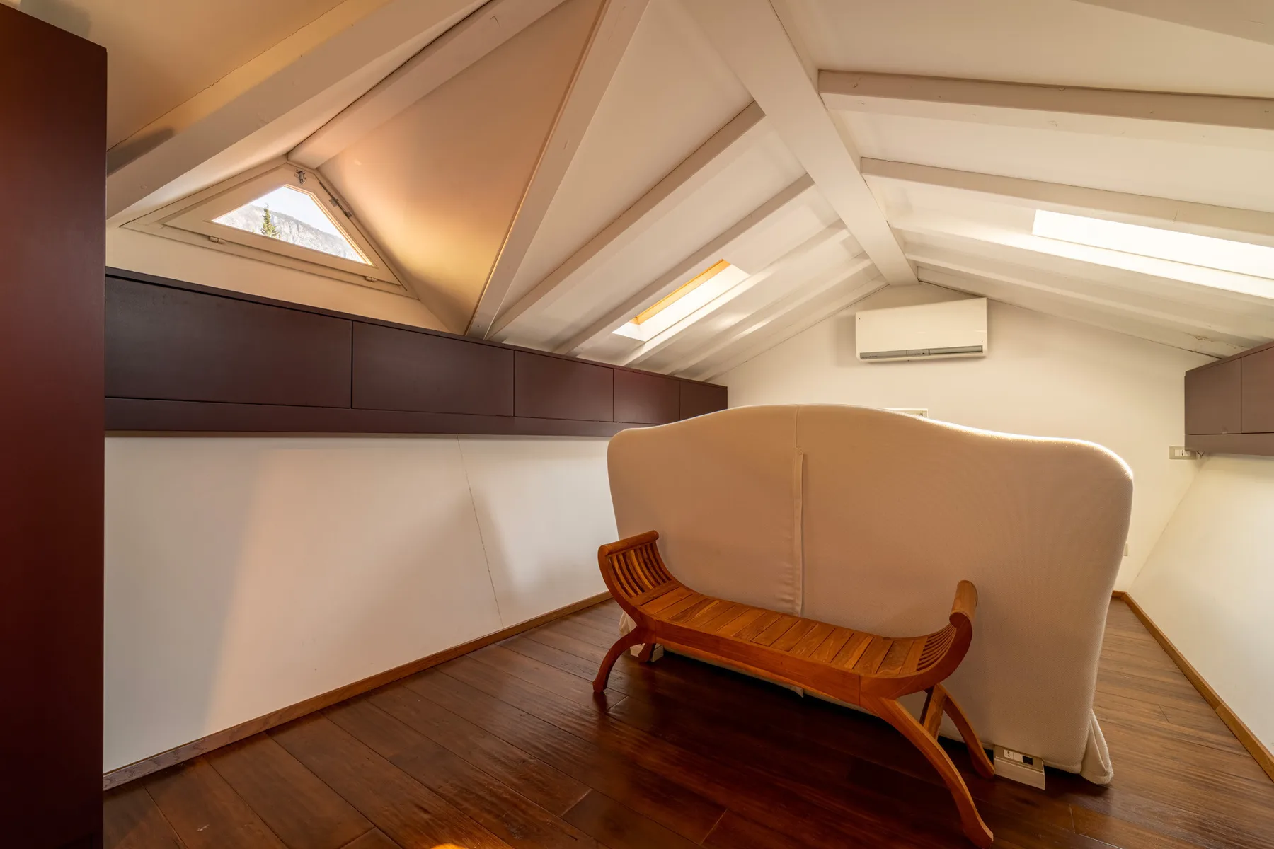 Un acogedor espacio abuhardillado con un banco de madera bajo el techo inclinado.
