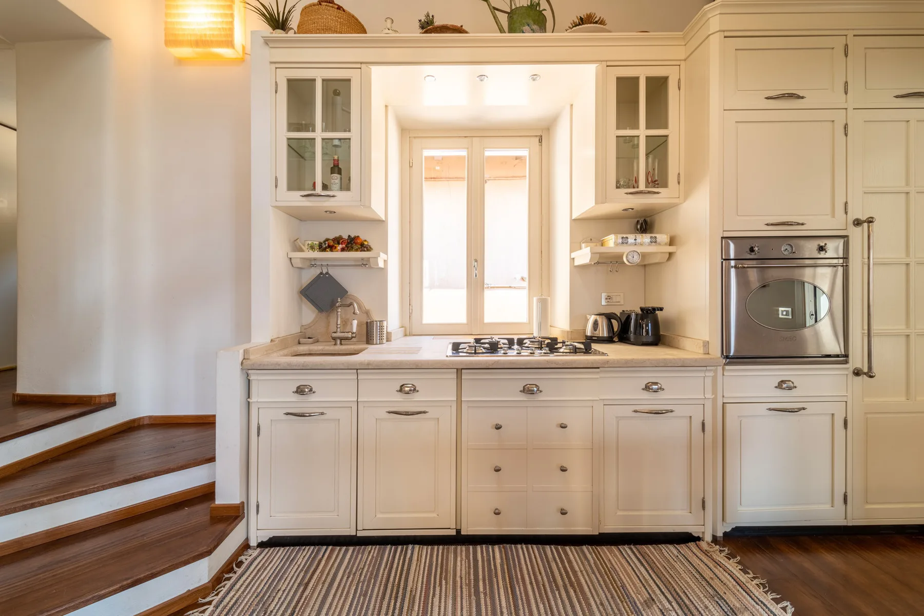 Una cocina luminosa con gabinetes blancos, una placa de cocción central y una ventana.