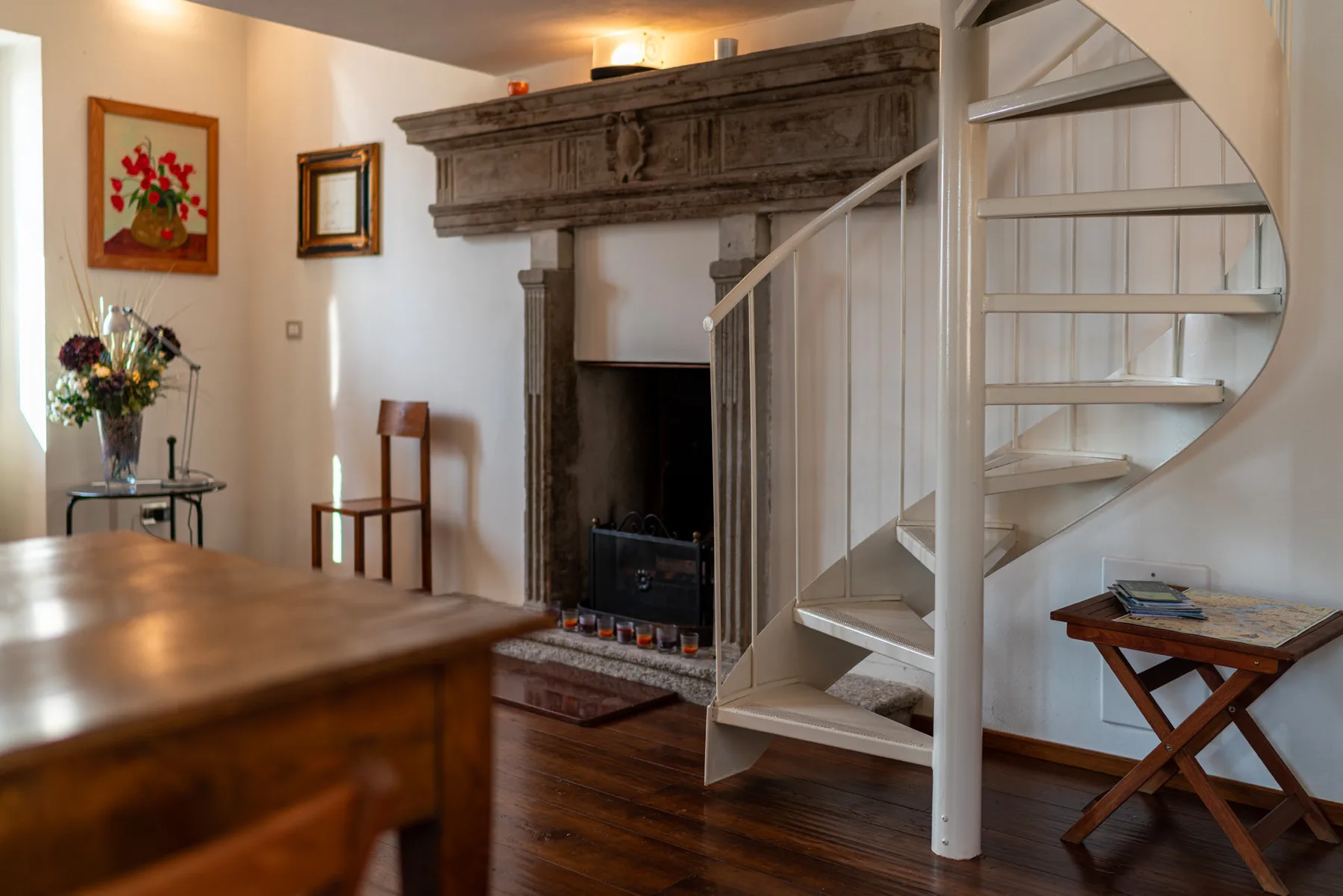 Una sala de estar con una chimenea de piedra y una escalera de caracol.