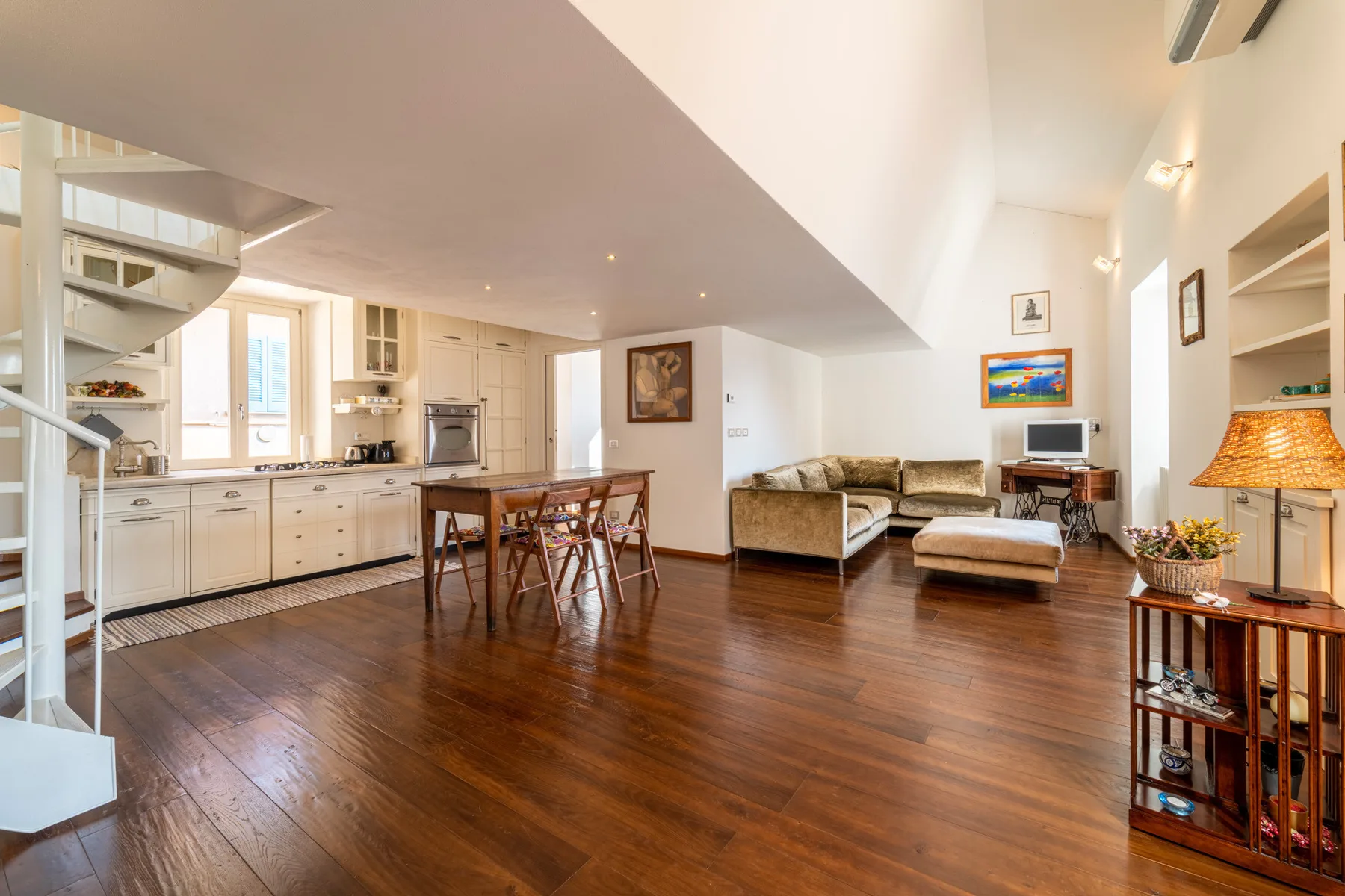 Una luminosa sala de estar y cocina de planta abierta, con suelo de madera y mesa de comedor.