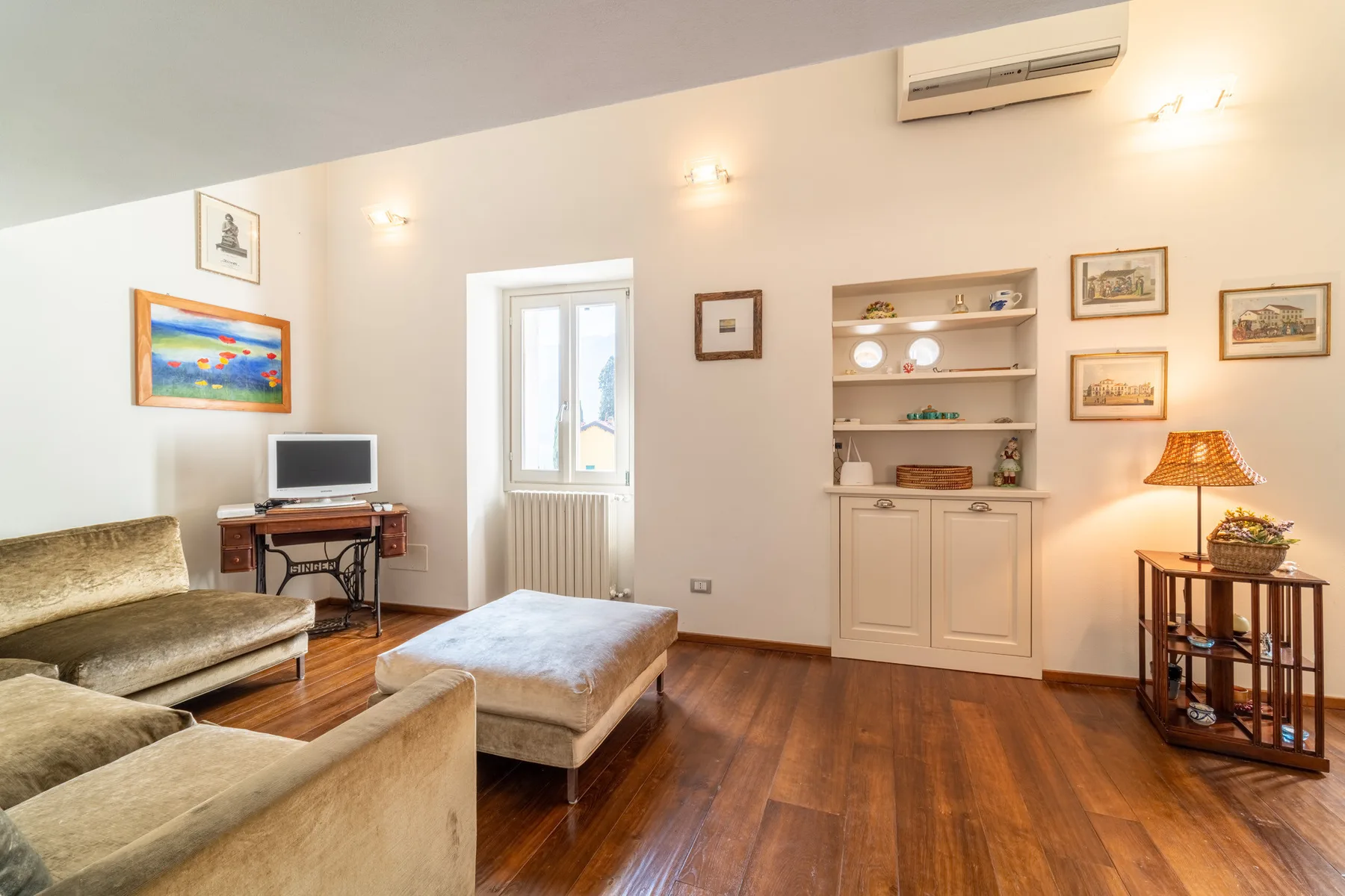 Una sala de estar con asientos, un televisor pequeño y estanterías empotradas.