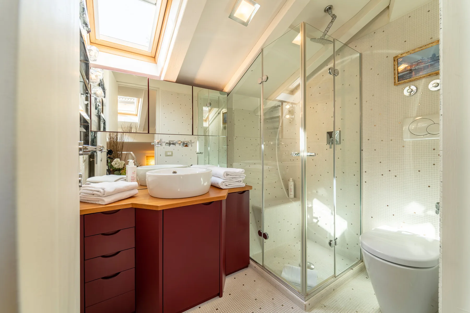 Un baño luminoso con tocador, lavabo y ducha de vidrio.