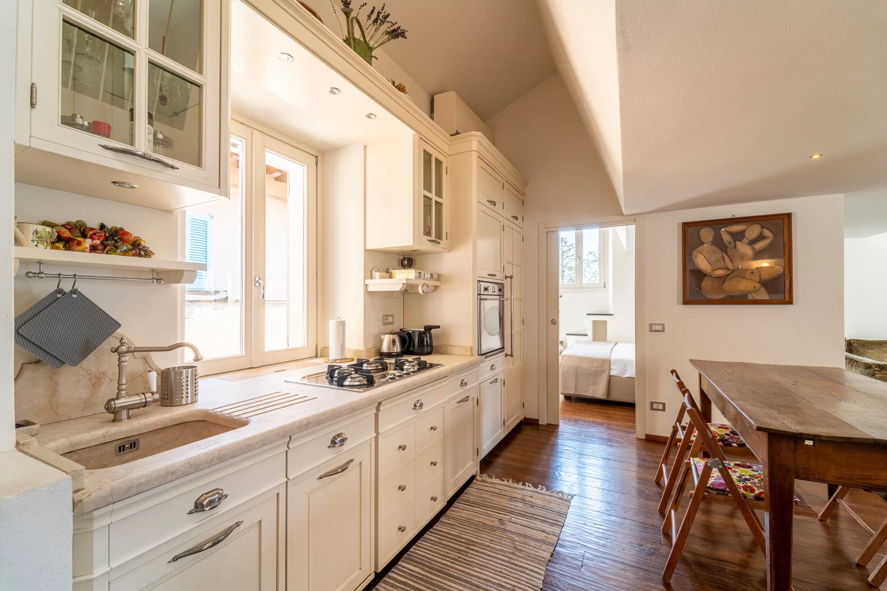 Una cocina luminosa con gabinetes blancos y una mesa de comedor al lado.