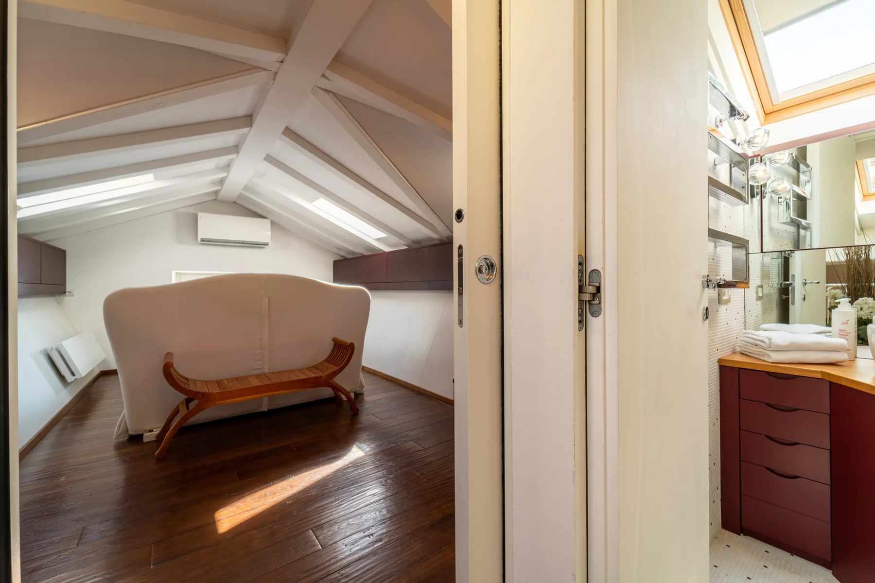 Un dormitorio tipo loft con una cama tapizada curva bajo un techo inclinado.