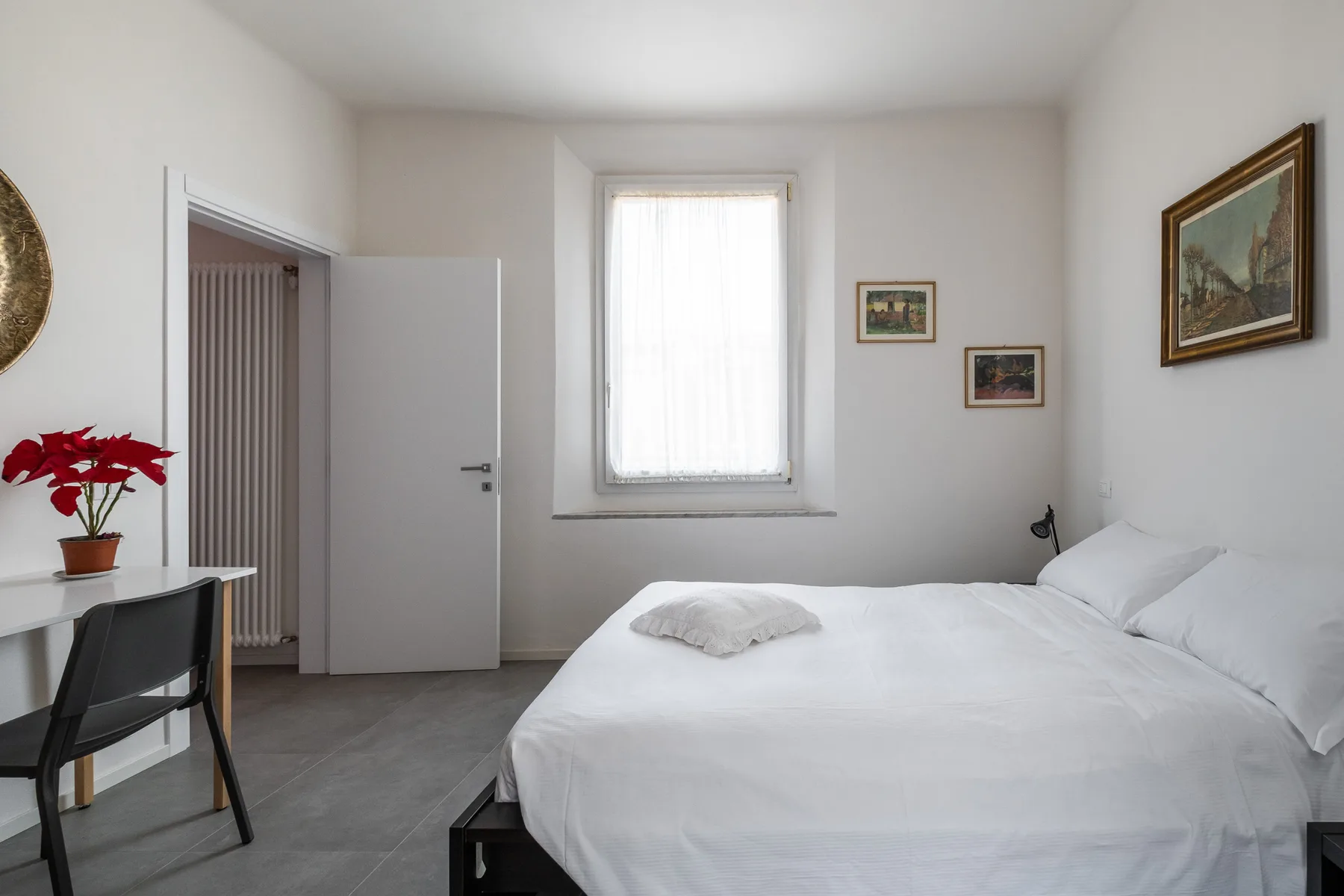 A bright bedroom with a neatly made bed and a window.