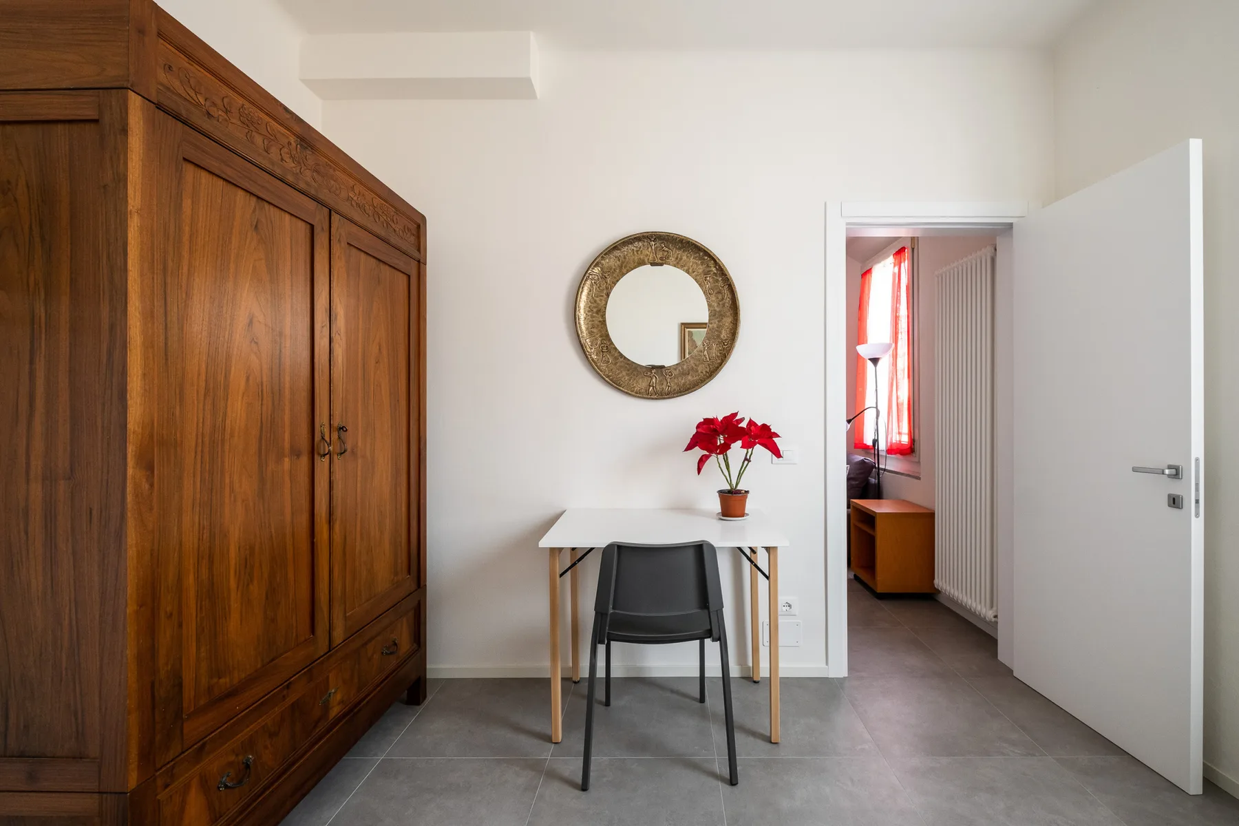 Una habitación sencilla con armario de madera, escritorio y puerta abierta.