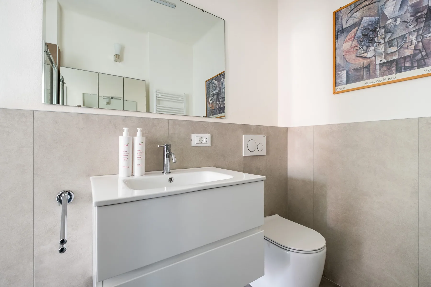 Un baño con lavabo, espejo e inodoro.