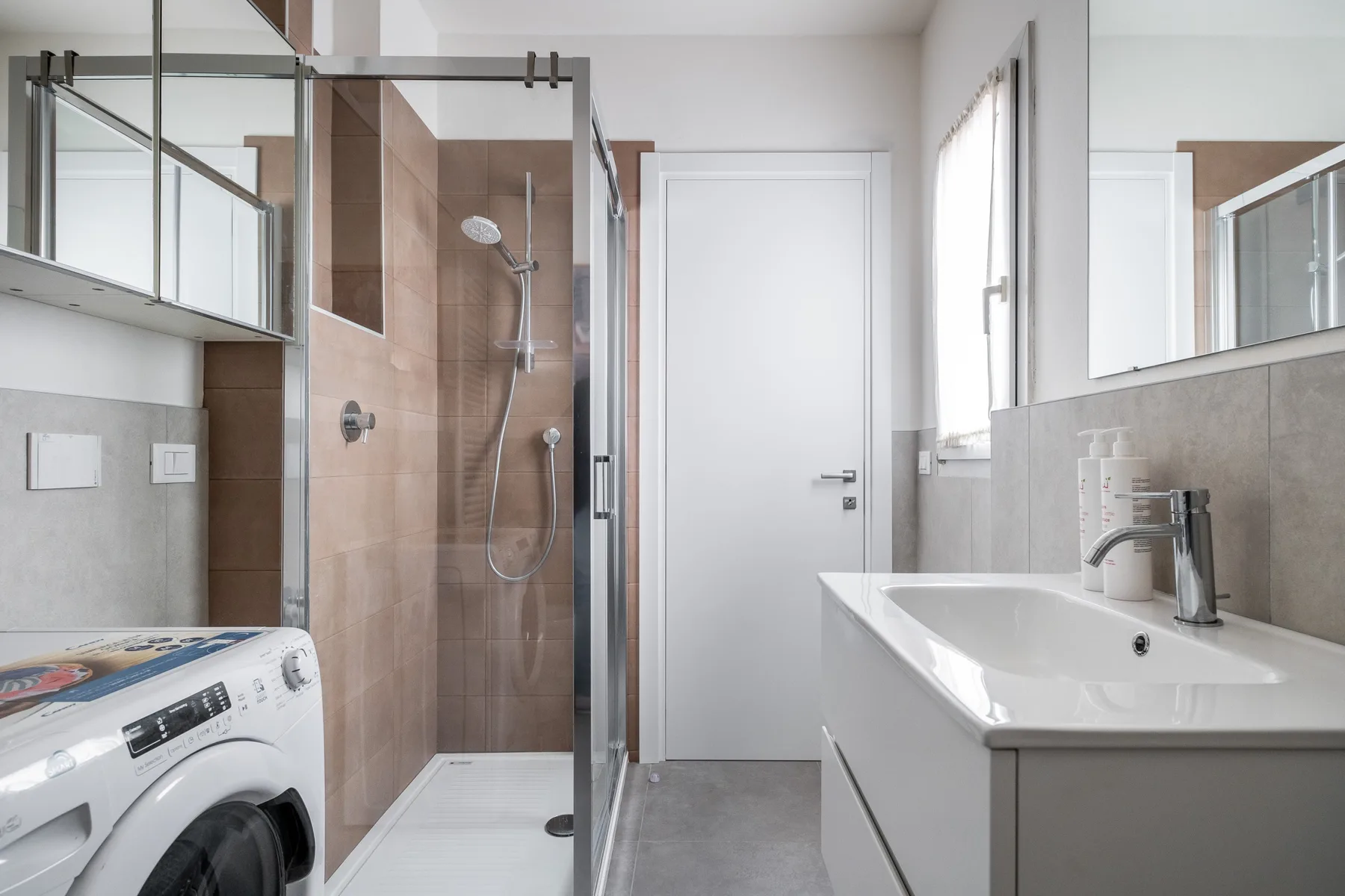 Un baño moderno con ducha de vidrio, bañera y lavadora.