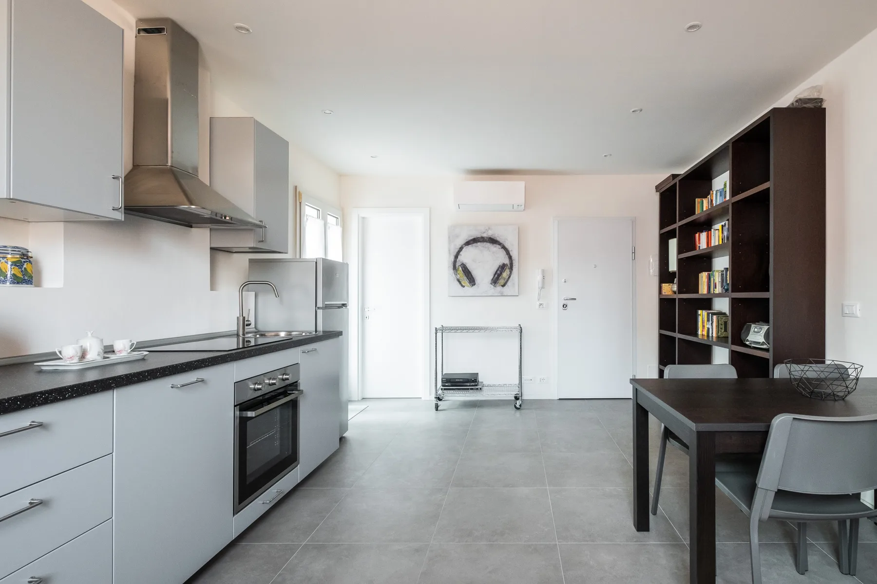 A bright kitchen and dining area with a counter, table, and open shelving.