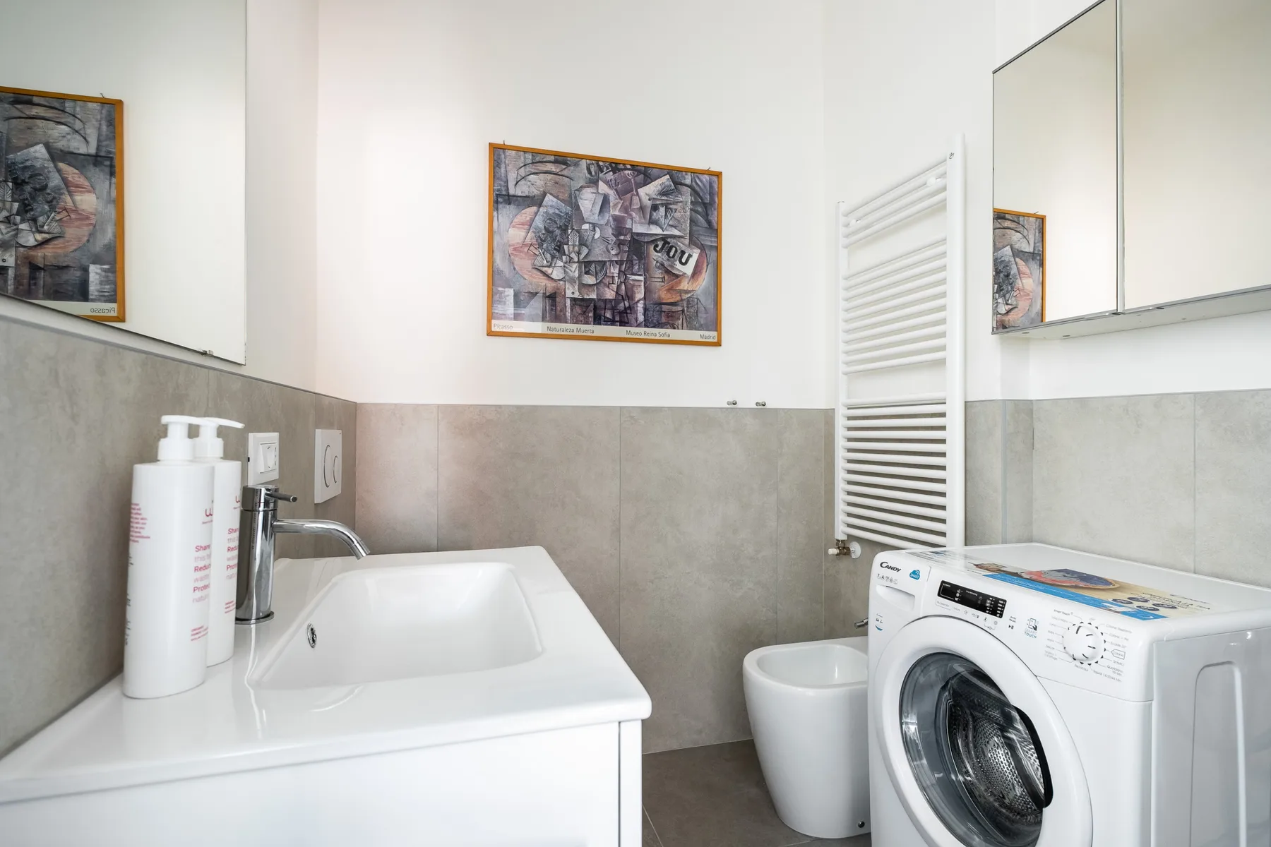 Un baño con lavabo, lavadora y toallero calefactable de pared.