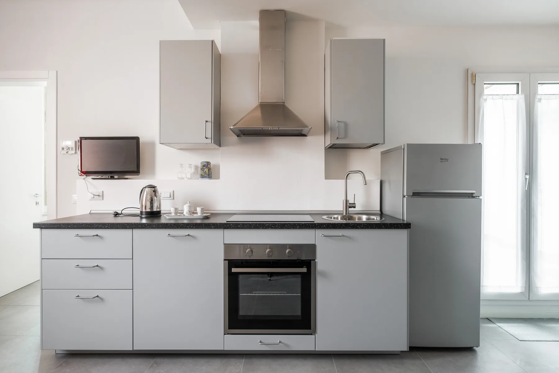 Una cocina moderna con armarios grises, una encimera y electrodomésticos integrados.