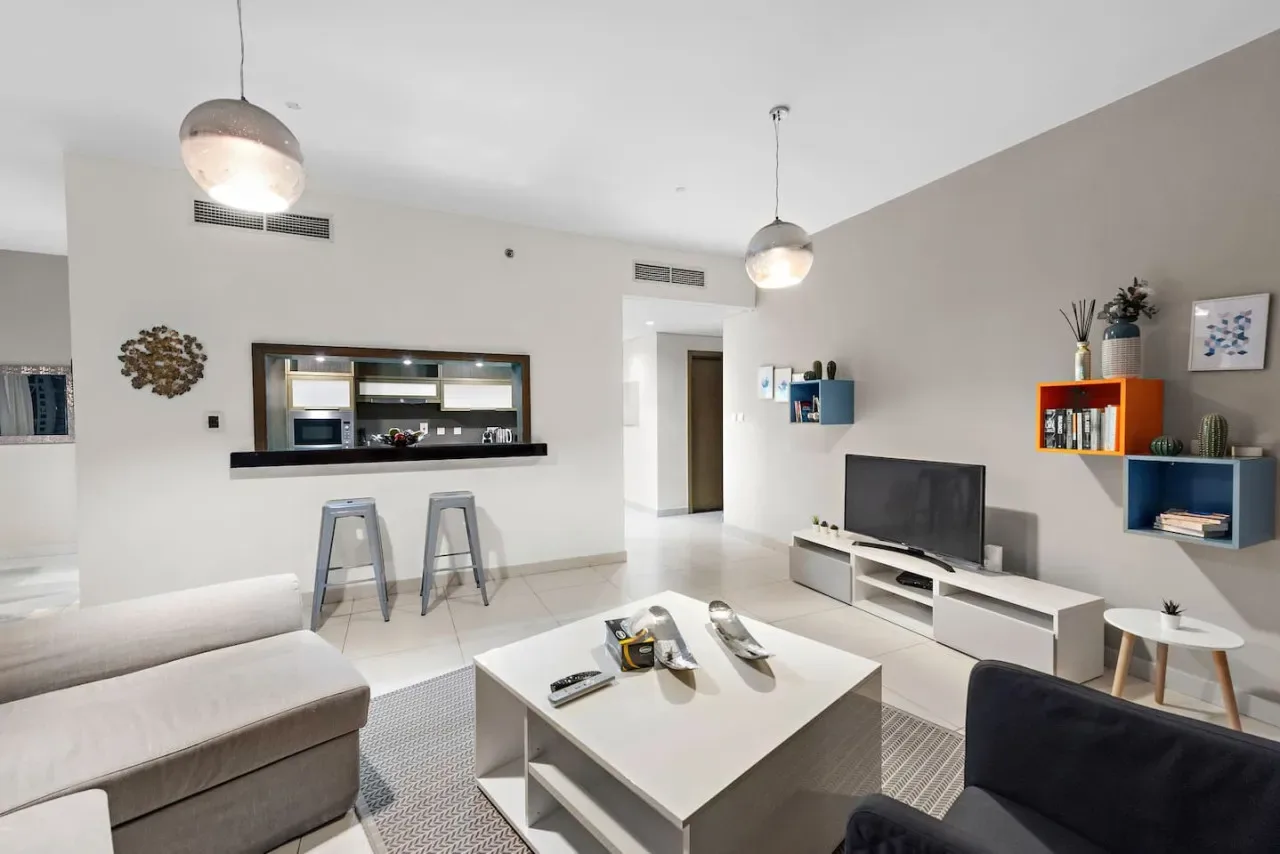 Una sala luminosa con televisor, mesa de centro y barra de desayuno.