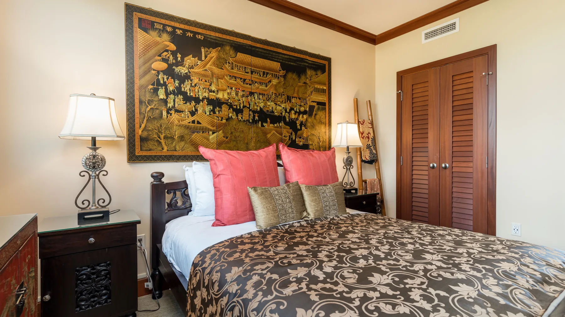 Un dormitorio con una cama, almohadas de colores y un gran tapiz decorativo.