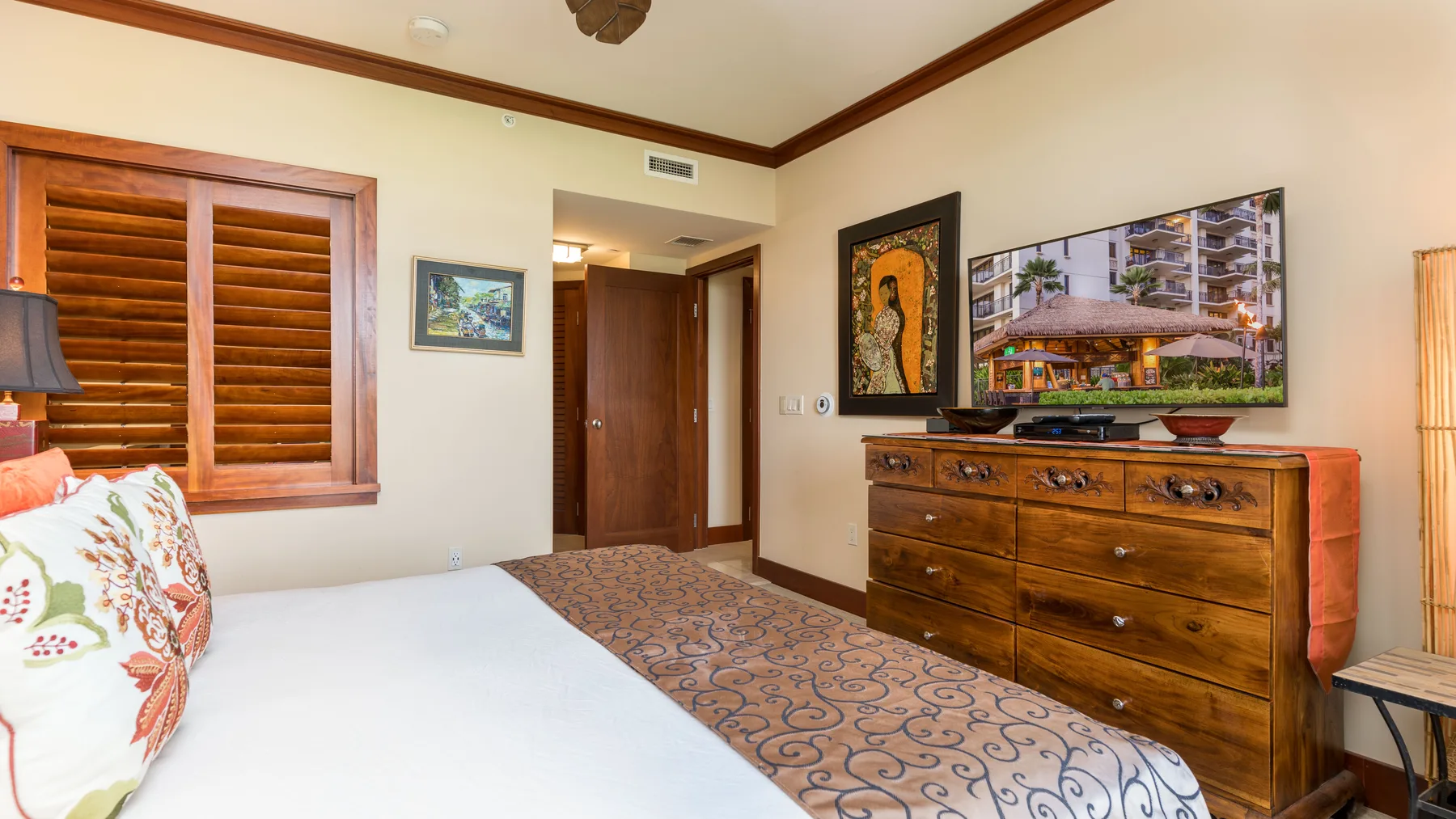 Un dormitorio con cama, cómoda de madera y ventana con contraventanas.