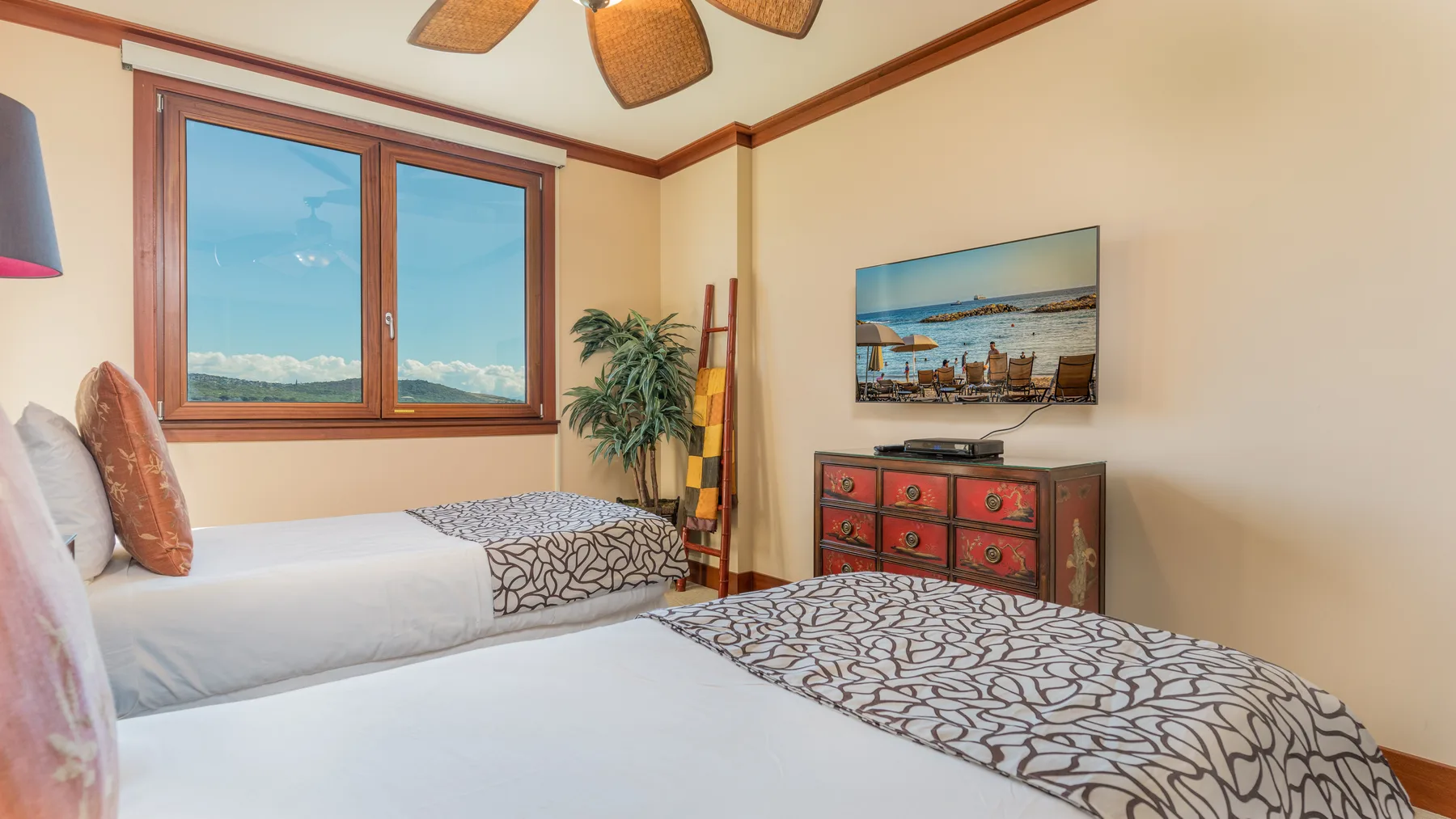 Un dormitorio con dos camas, una ventana y una cómoda bajo un televisor.