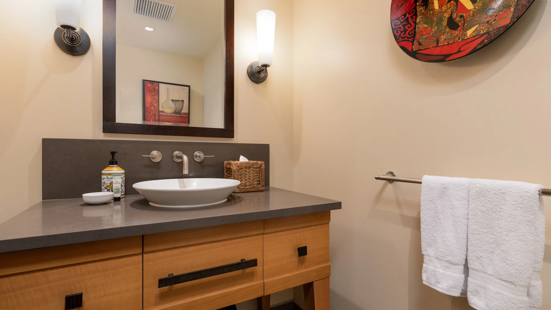 Un tocador de baño con lavabo, espejo de pared y toallas.