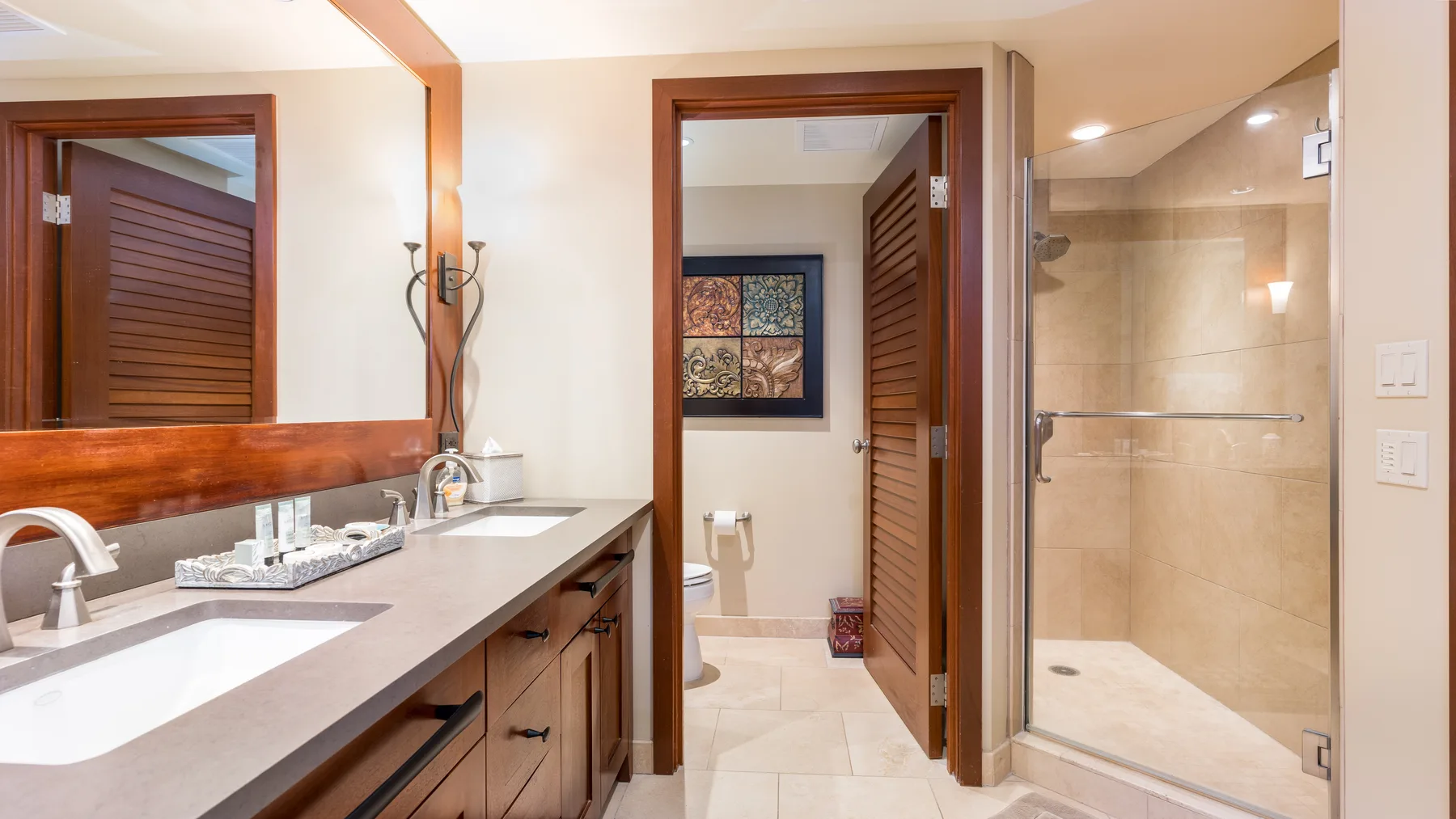Se ven un lavabo de baño y una ducha con mampara de vidrio junto a una puerta abierta.
