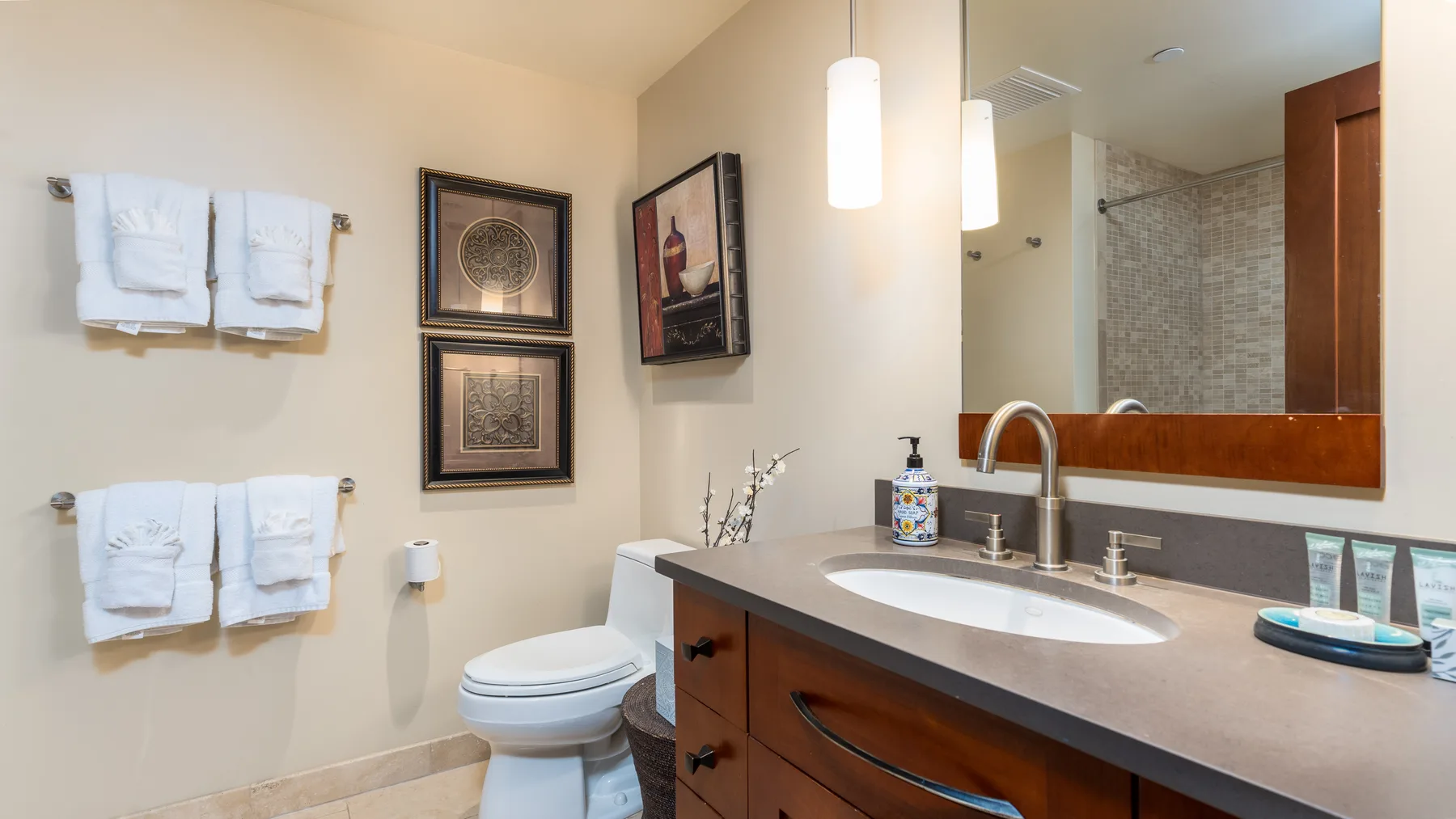 Un lavabo de baño está junto a un inodoro y toallas colgadas en la pared.