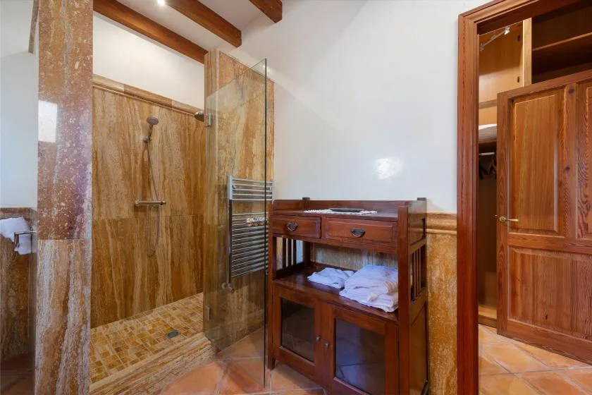 Un baño con una ducha de vidrio y un mueble de madera.
